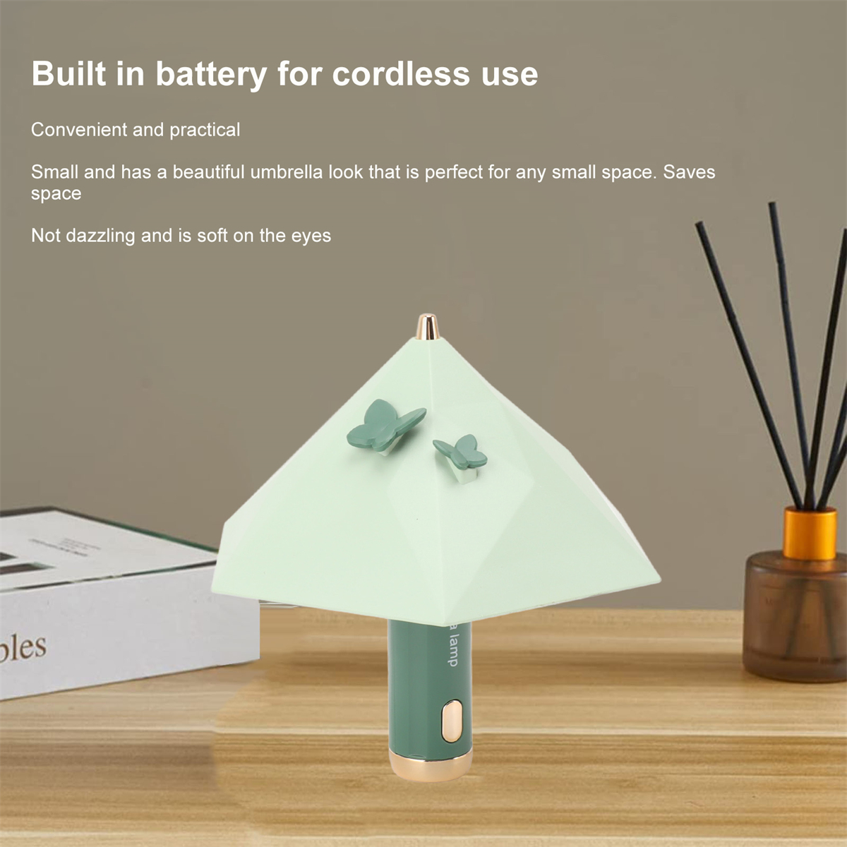 Eine mintgrüne schirmförmige Lampe mit Schmetterlingen. Sie hat einen grünen Sockel und einen weißen Kopf.