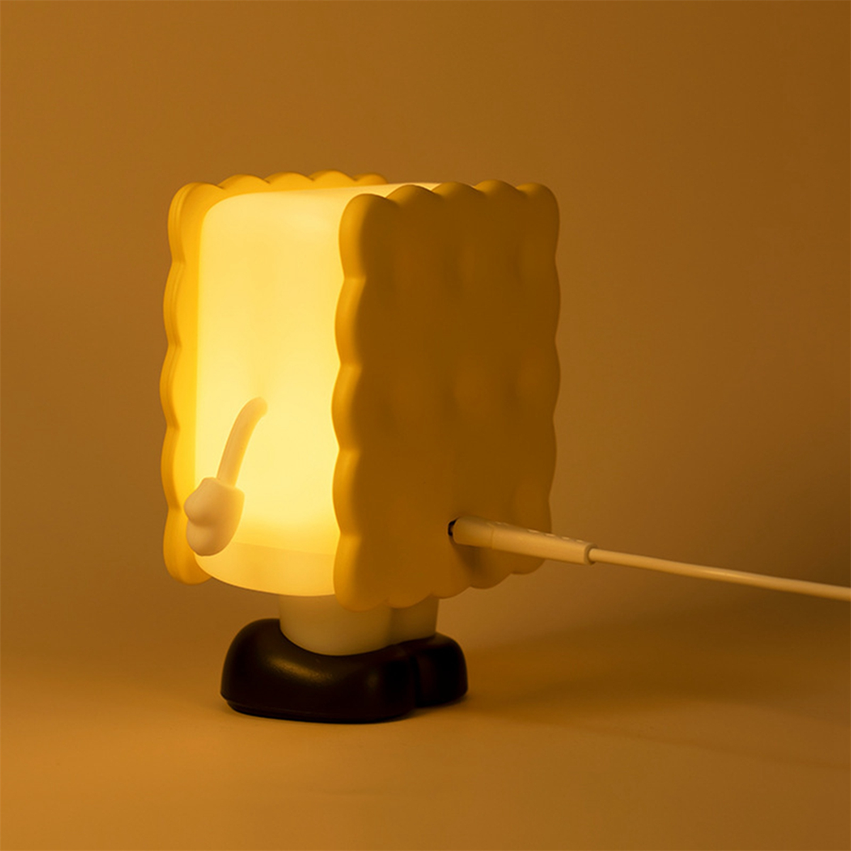 Gelbe Keksförmige Lampe mit weißem Kabel. Dunkelgelber/oranger Hintergrund.