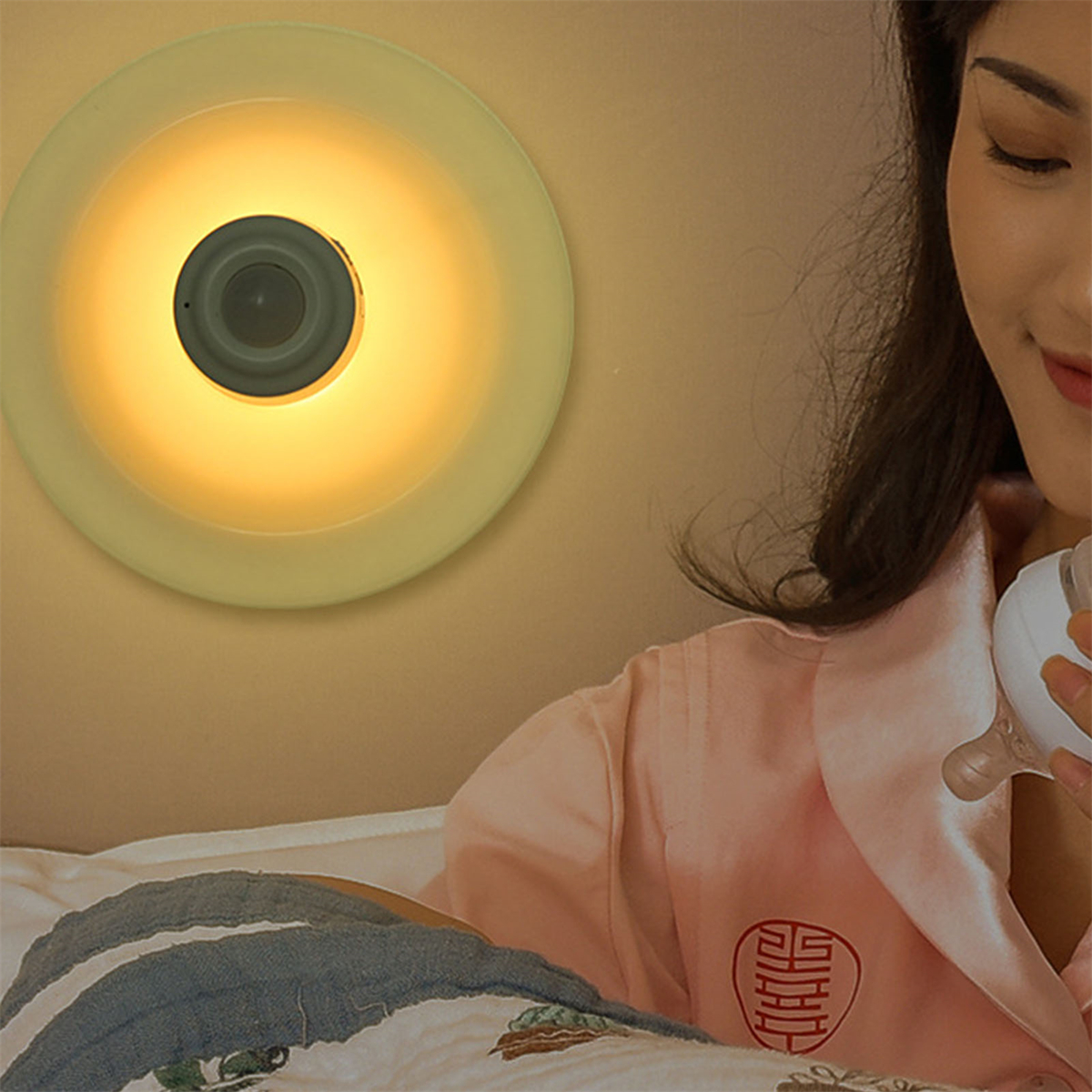 Eine Frau liegt in einem Bett mit einem Nachtlicht. Das Licht ist rund und gelb und an der Wand.