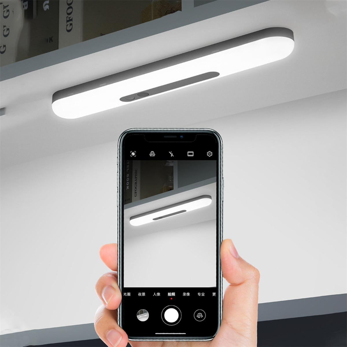 Eine Person macht mit einem Telefon ein Foto eines langen, weißen LED-Lichts. Das Licht ist an einem Regal montiert.