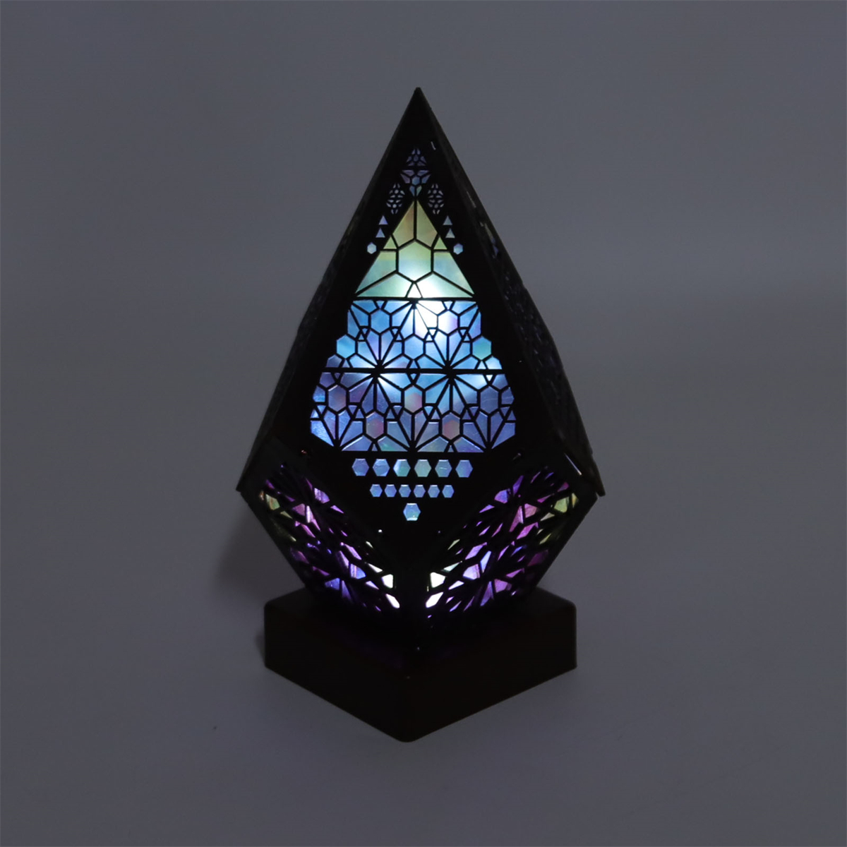Schwarze dekorative Lampe mit geometrischem Design, mehrfarbig beleuchtet.