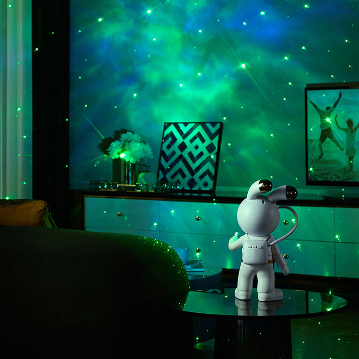 Raum mit grünem Sternprojektor. Eine weiße Weltraummann-Figur steht auf einem Tisch, und ein Fernseher.