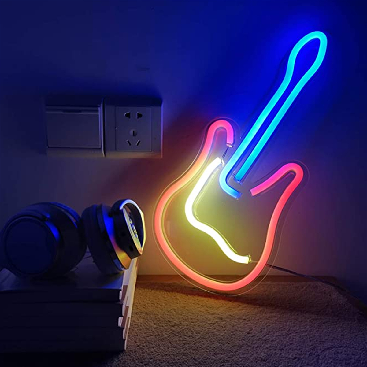 Ein Neon-Gitarrenschild mit blauem Hals und rotem Korpus. Es befindet sich an einer Wand über einem Tisch.