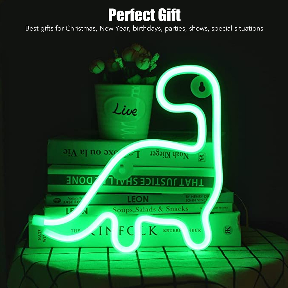 Grüne Neon-Dinosaurierlampe auf Büchern, mit einem Blumentopf.