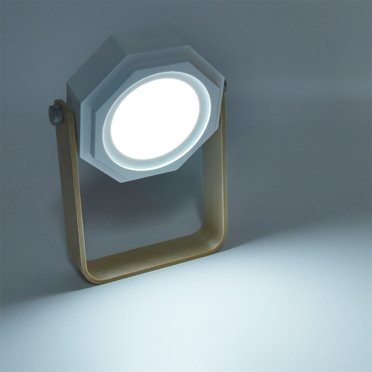 Eine weiße und holzfarbene Lampe mit hellem Licht, das auf einem weißen Hintergrund scheint.
