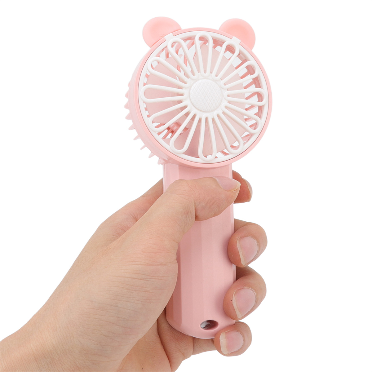 Rosa Mini-Ventilator, der von einer Hand gehalten wird. Der Ventilator hat einen Griff und eine runde Oberfläche.