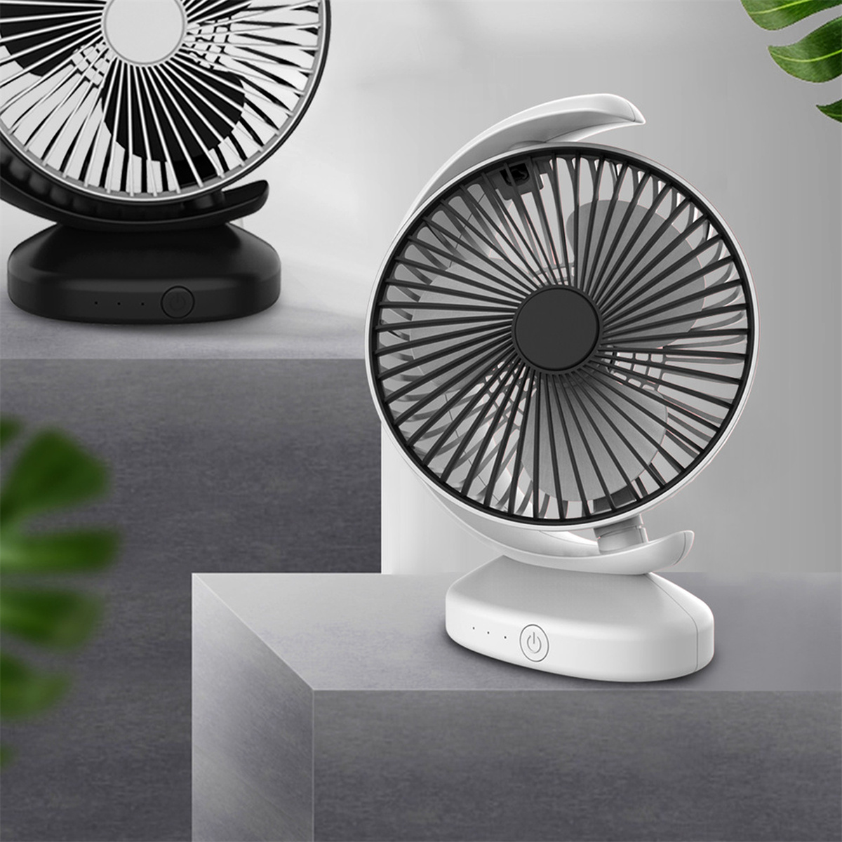 Zwei weiße und schwarze Ventilatoren auf einer grauen Oberfläche. Einer hat einen Einschaltknopf.