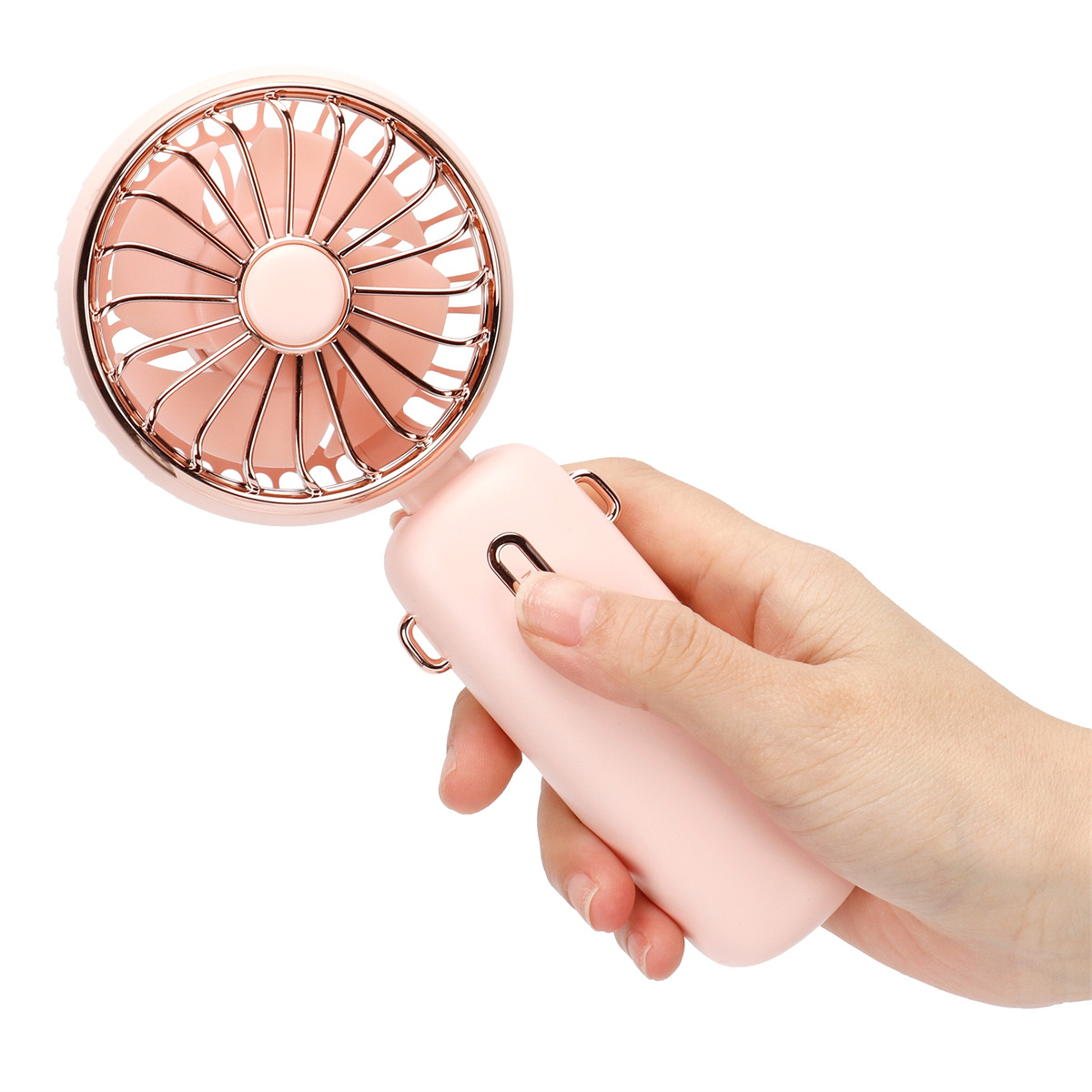 Eine Hand hält einen rosa, roségoldenen Handventilator. Der Ventilator hat ein Schutzgitter.