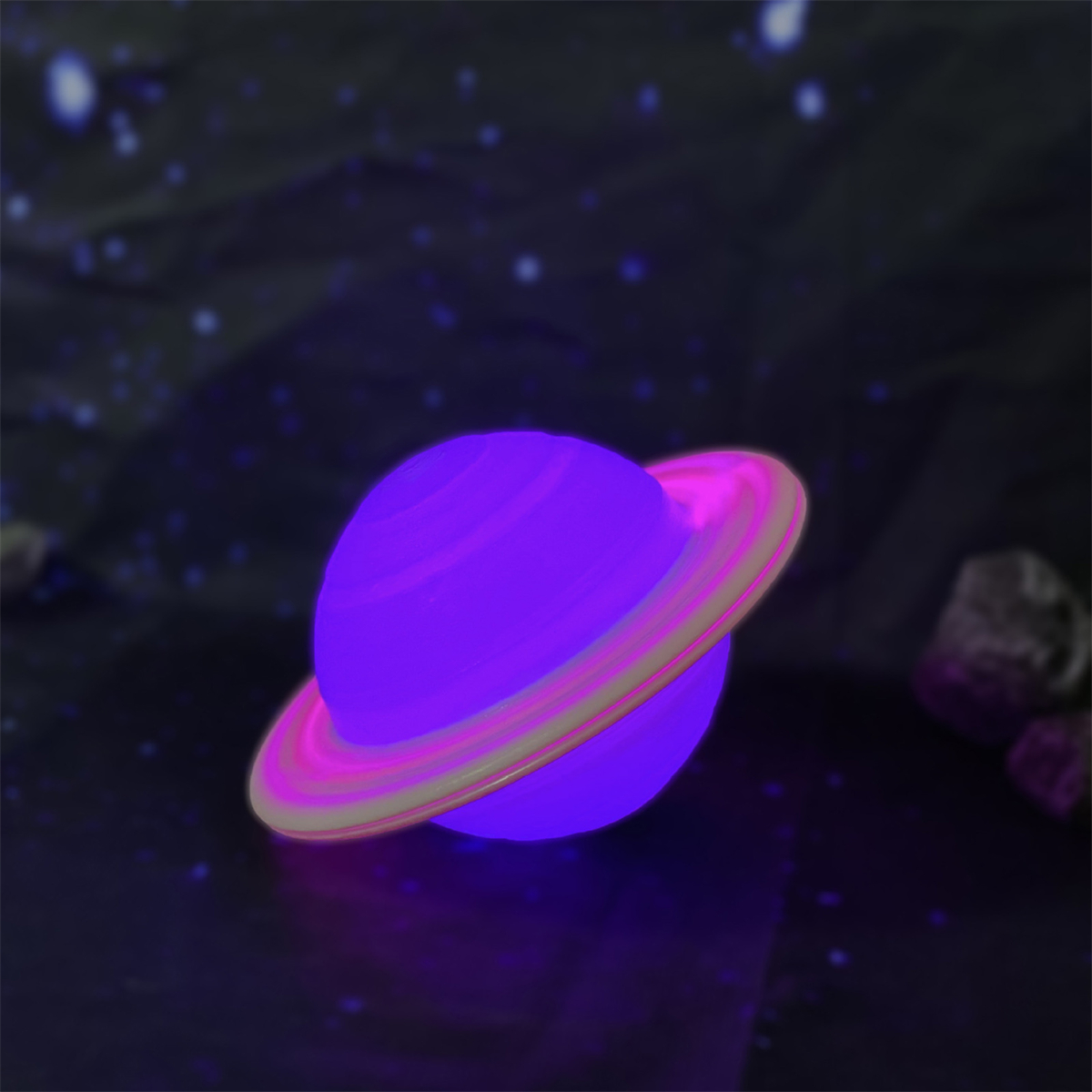 Ein lila Planet mit Ringen und einem Licht. Der Planet befindet sich auf einer dunklen Oberfläche.