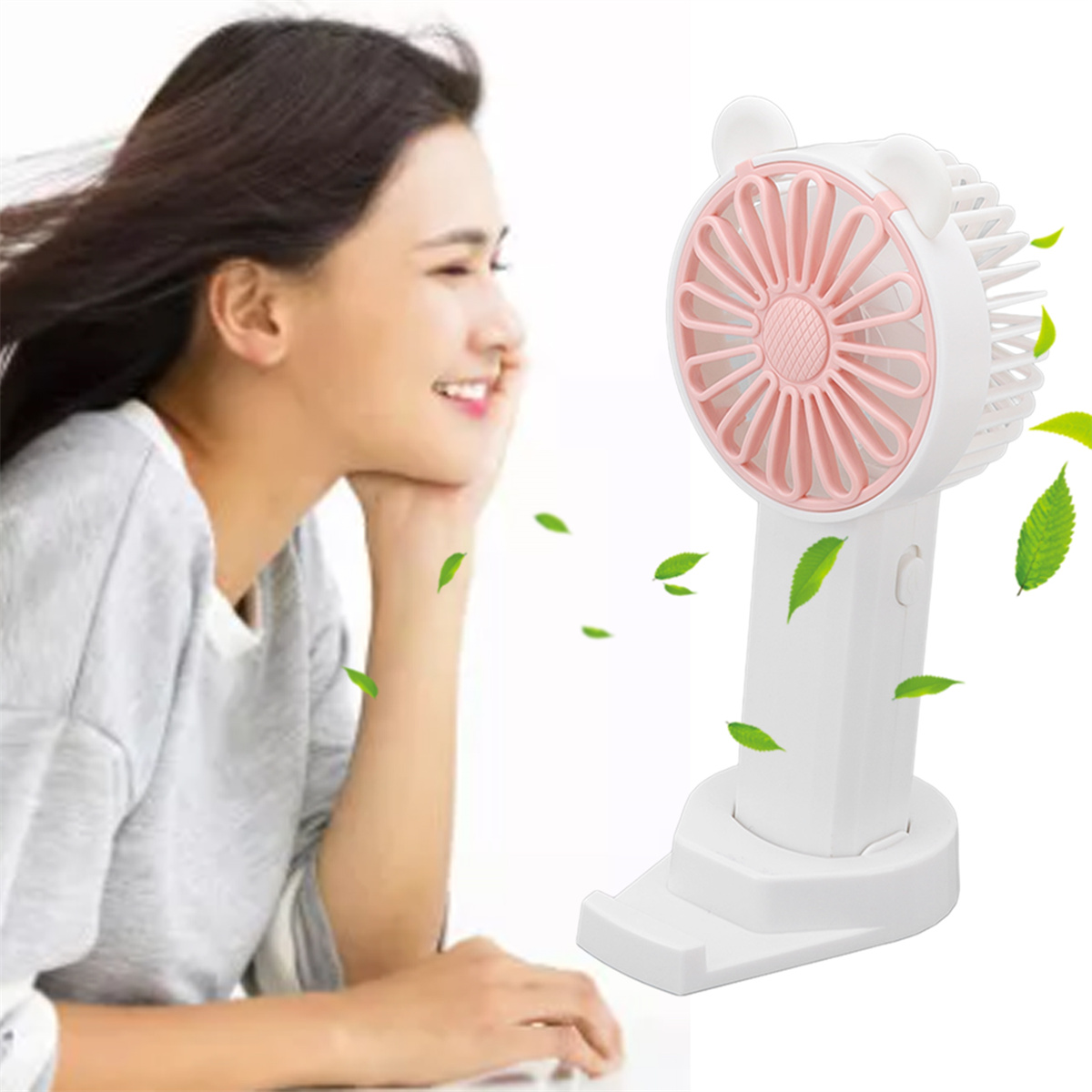 Eine Frau mit einem Ventilator in der Hand. Der Ventilator ist weiß und rosa mit grünen Blättern.