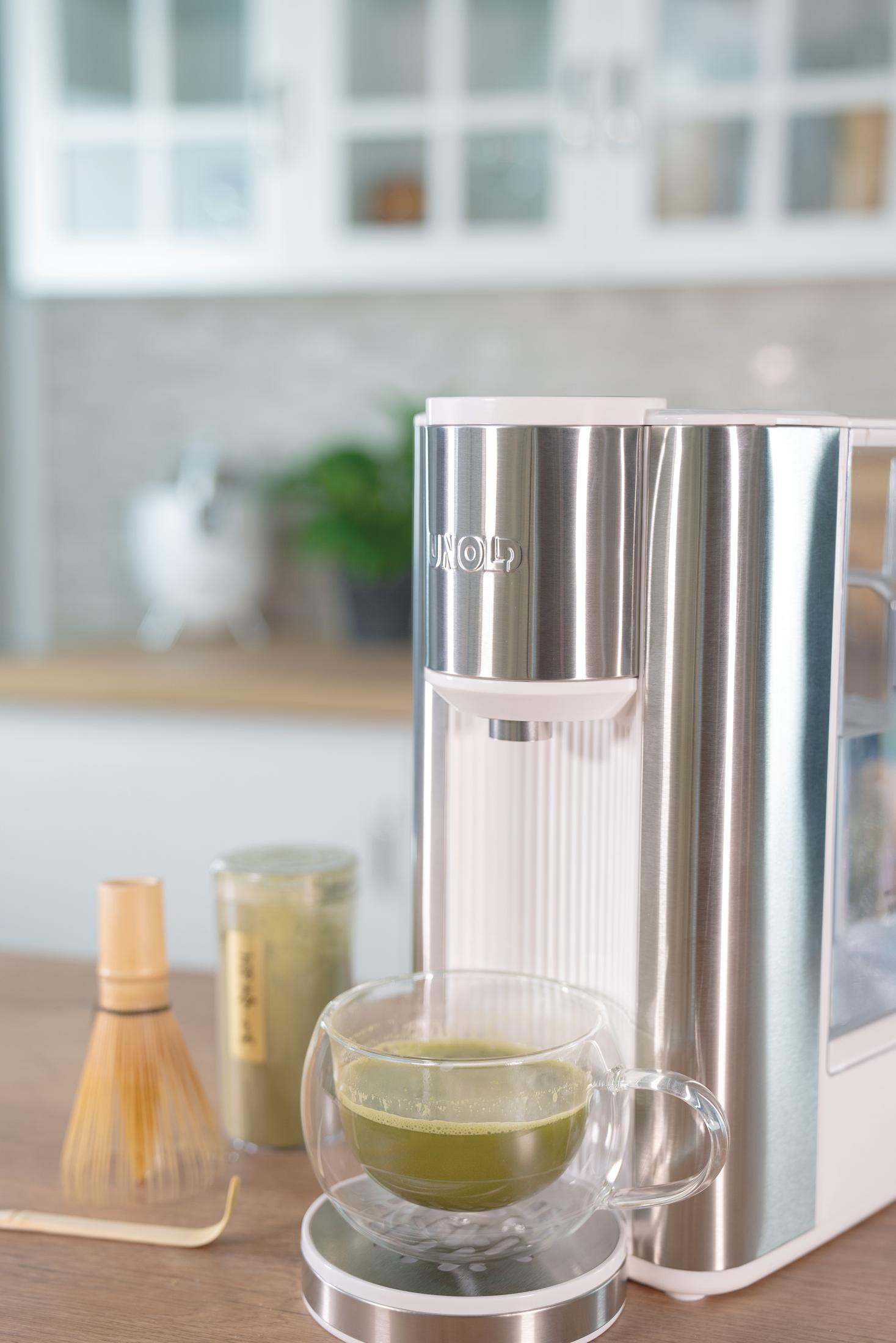 Matcha-Teebereiter mit einer Tasse Grüntee, Schneebesen und Matcha-Pulver-Glas.