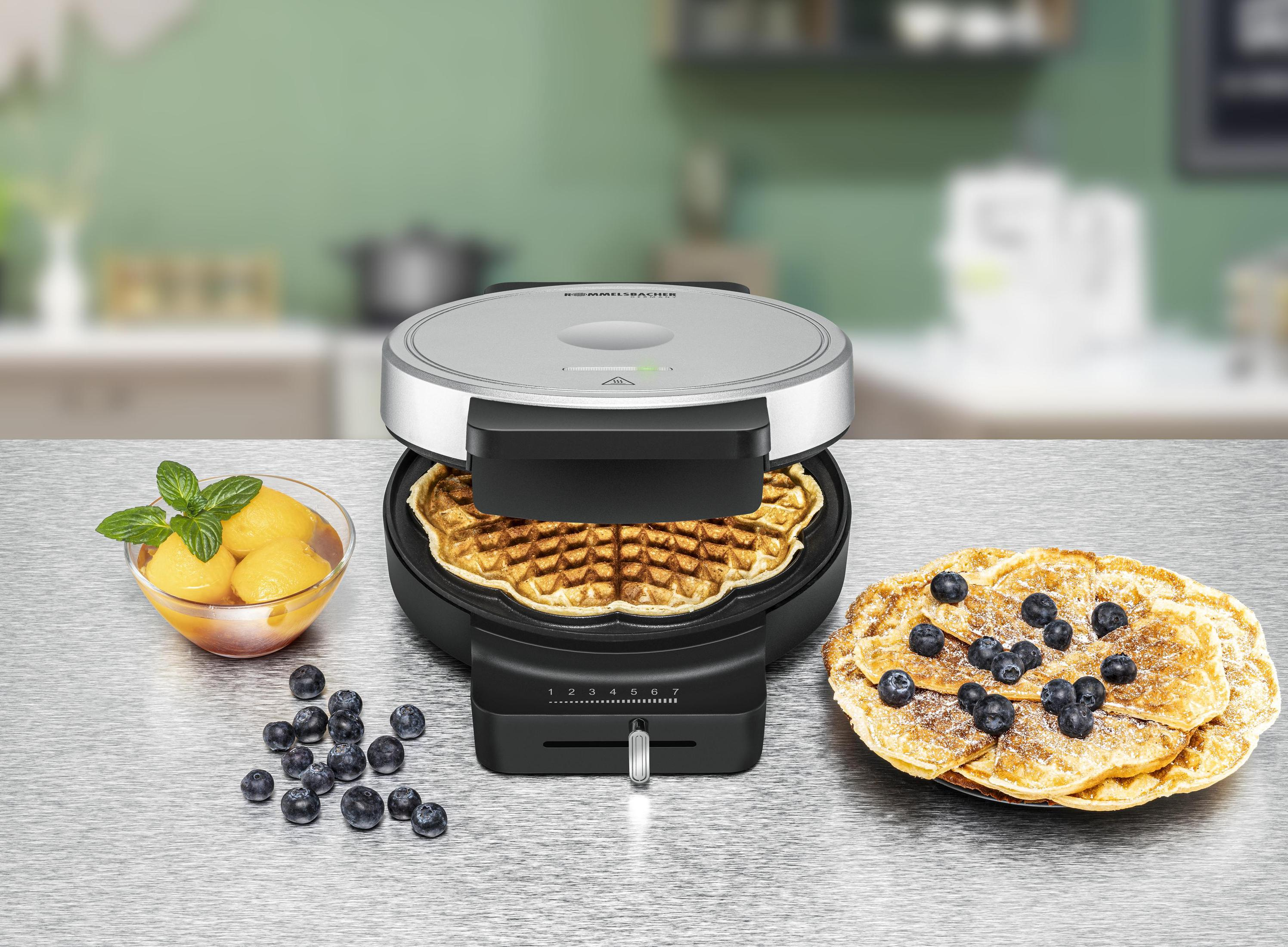 Gofrownica z goframi. Jagody na gofrach. Miseczka z brzoskwiniami i miętą. Jasne tło.