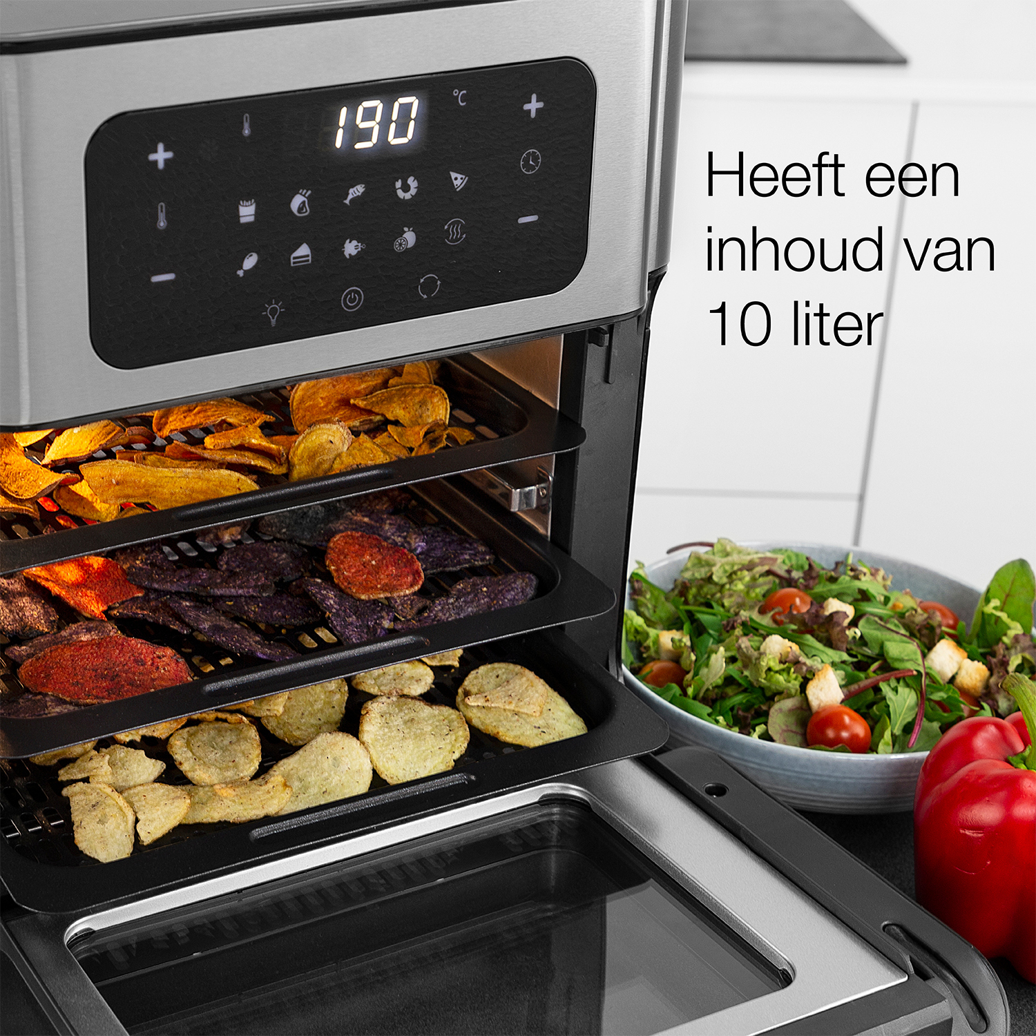 Frytkownica powietrzna z jedzeniem w środku, a obok sałatka i czerwona papryka.