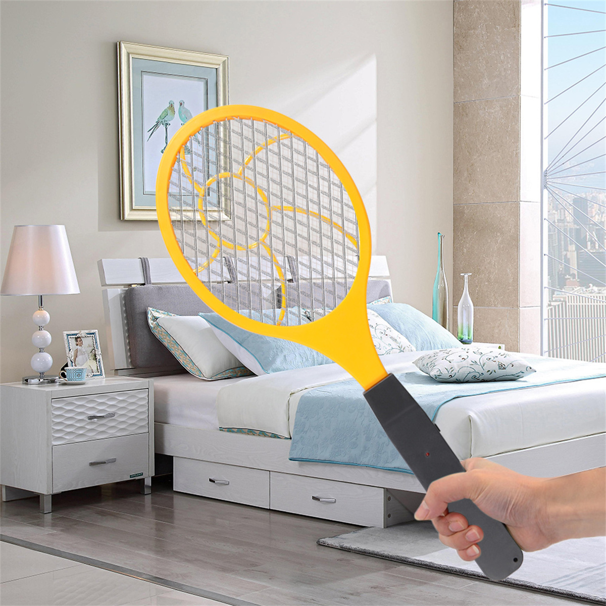 Ein gelber elektrischer Moskitoschläger, der von einer Hand gehalten wird, in einem Schlafzimmer mit Bett.