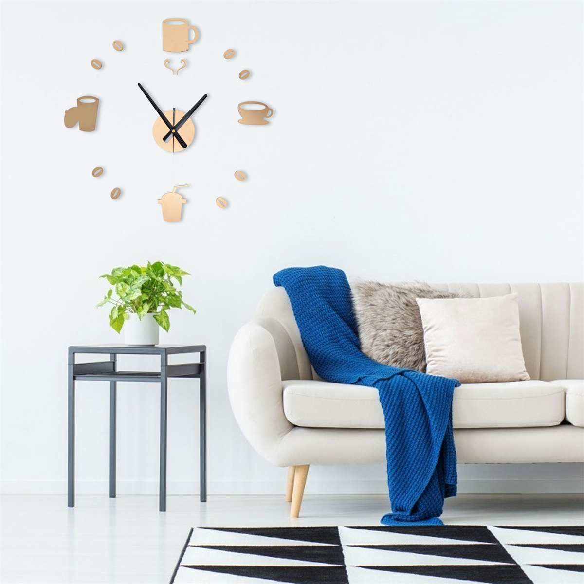 Eine Wanduhr mit Kaffeebechern und Bohnen-Design. Ein Sofa mit Kissen und Decke.