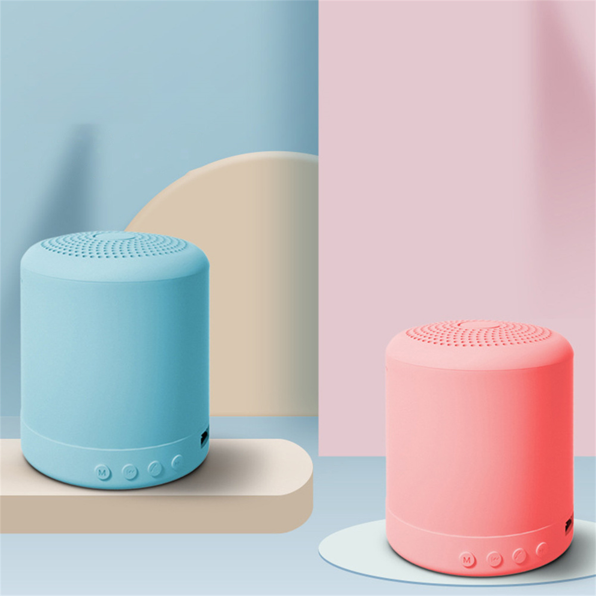 Zwei kleine, zylindrische Lautsprecher. Einer ist blau, der andere rosa. Sie stehen auf einer hellen Plattform.