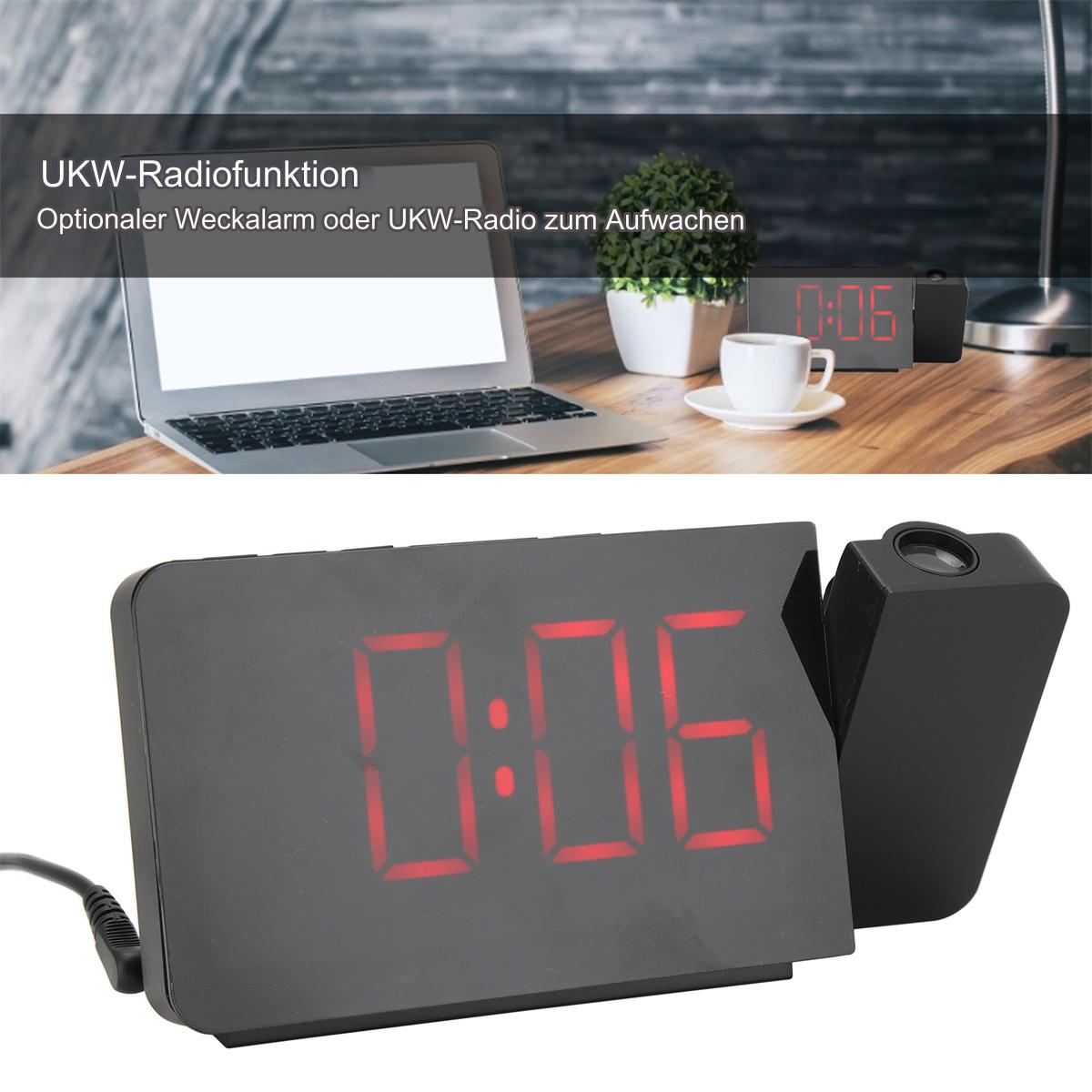Ein digitaler Wecker mit roten Ziffern. Ein Laptop und eine Kaffeetasse befinden sich im Hintergrund.