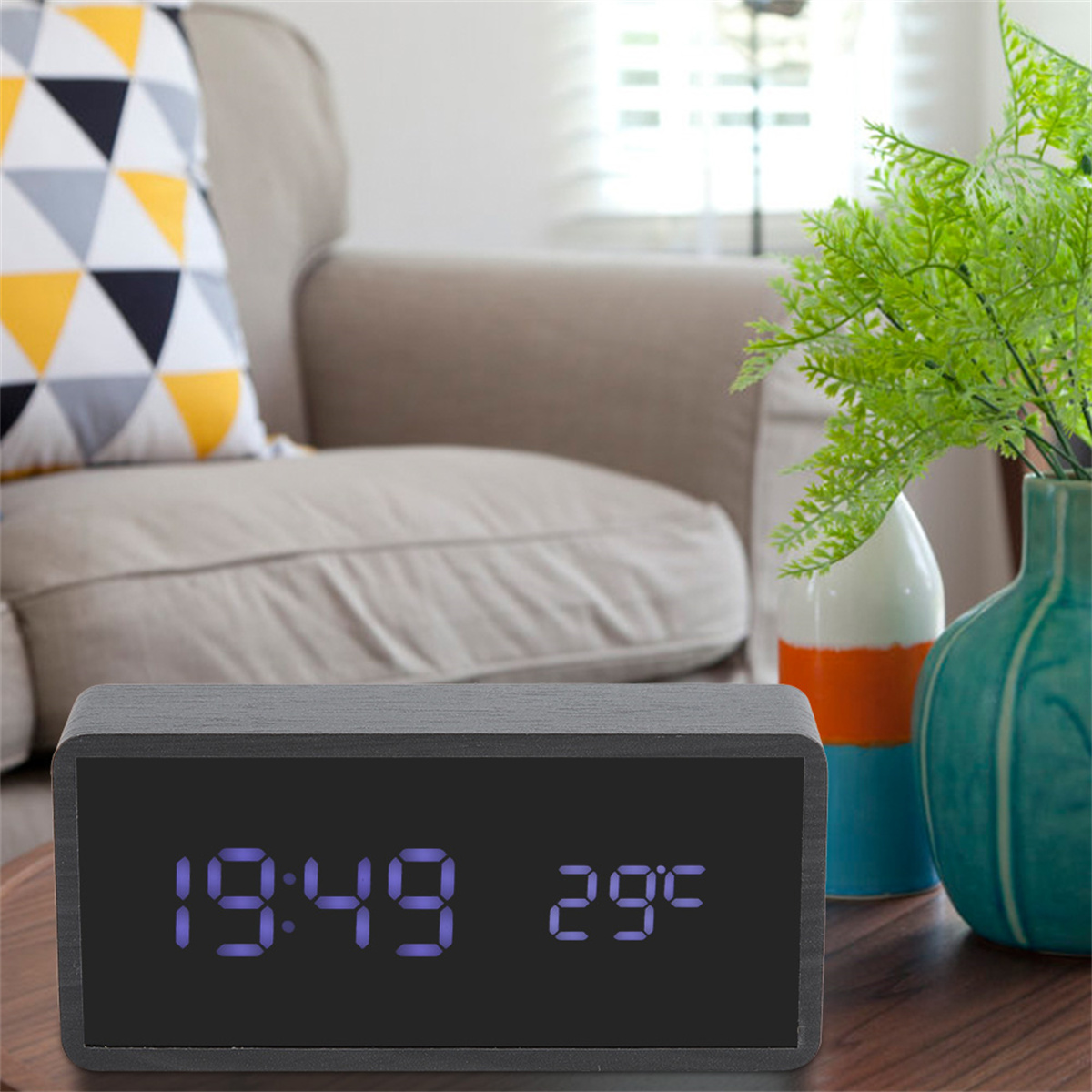 Hölzerne Digitaluhr, die Zeit und Temperatur anzeigt. Wohnzimmer im Hintergrund.