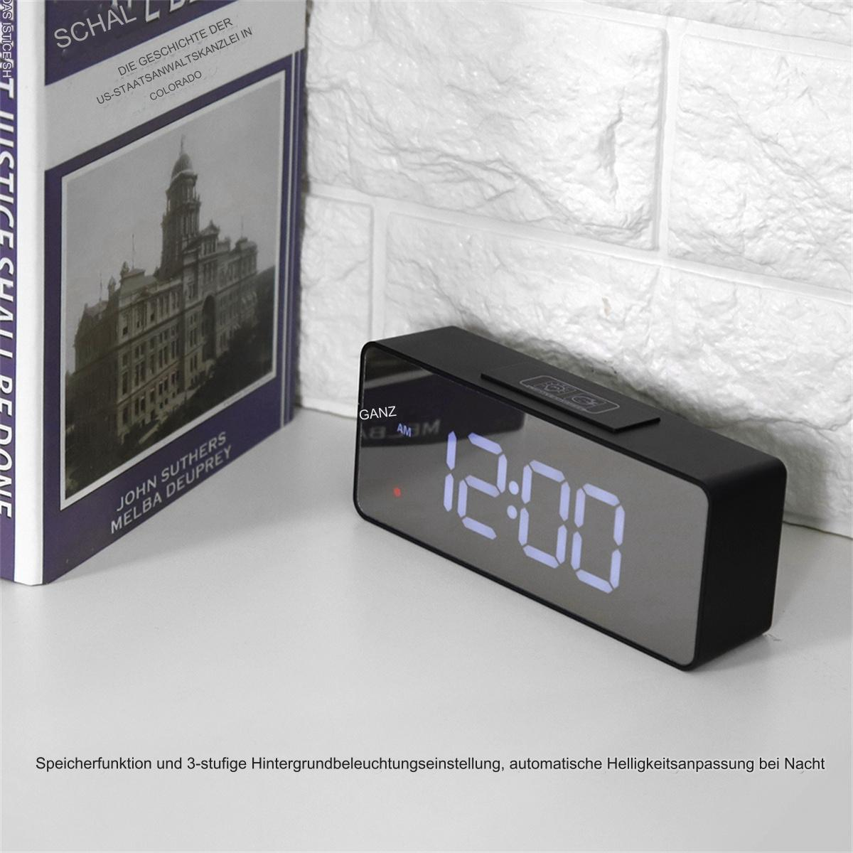 Schwarze Digitaluhr zeigt 12:00. Die Uhr steht auf weißer Oberfläche.