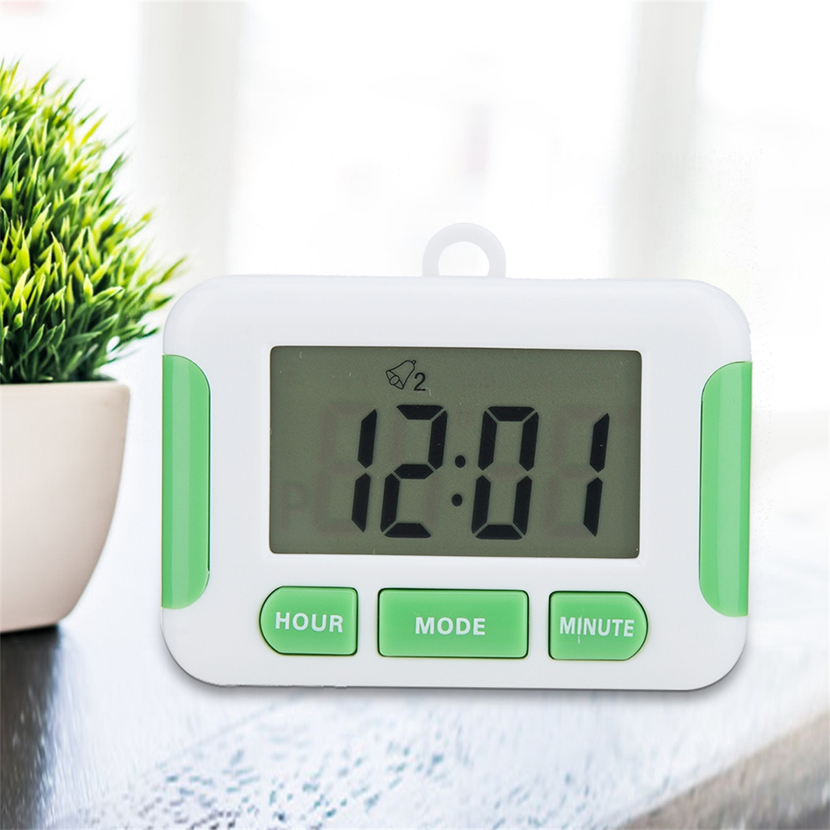 Ein kleiner, weiß-grüner digitaler Timer mit der Anzeige 12:01. Er hat drei grüne Knöpfe.