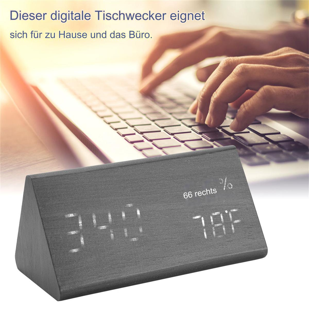 Ein digitaler Wecker aus Holz zeigt Zeit und Temperatur, Laptop im Hintergrund.