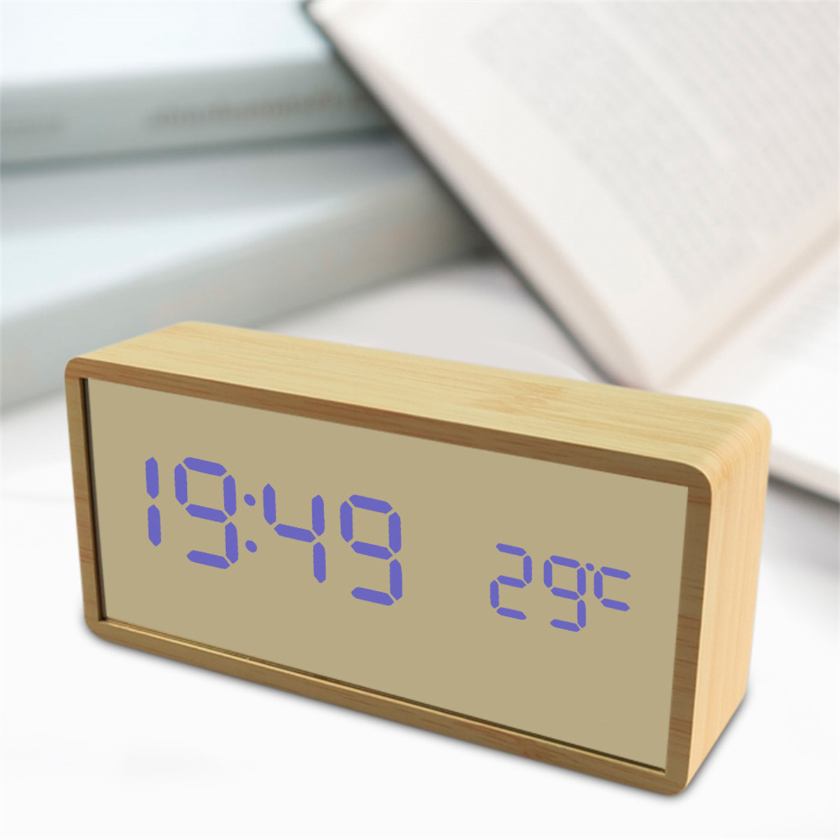Eine digitale Holzuhr, die Zeit und Temperatur anzeigt, mit Büchern im Hintergrund.