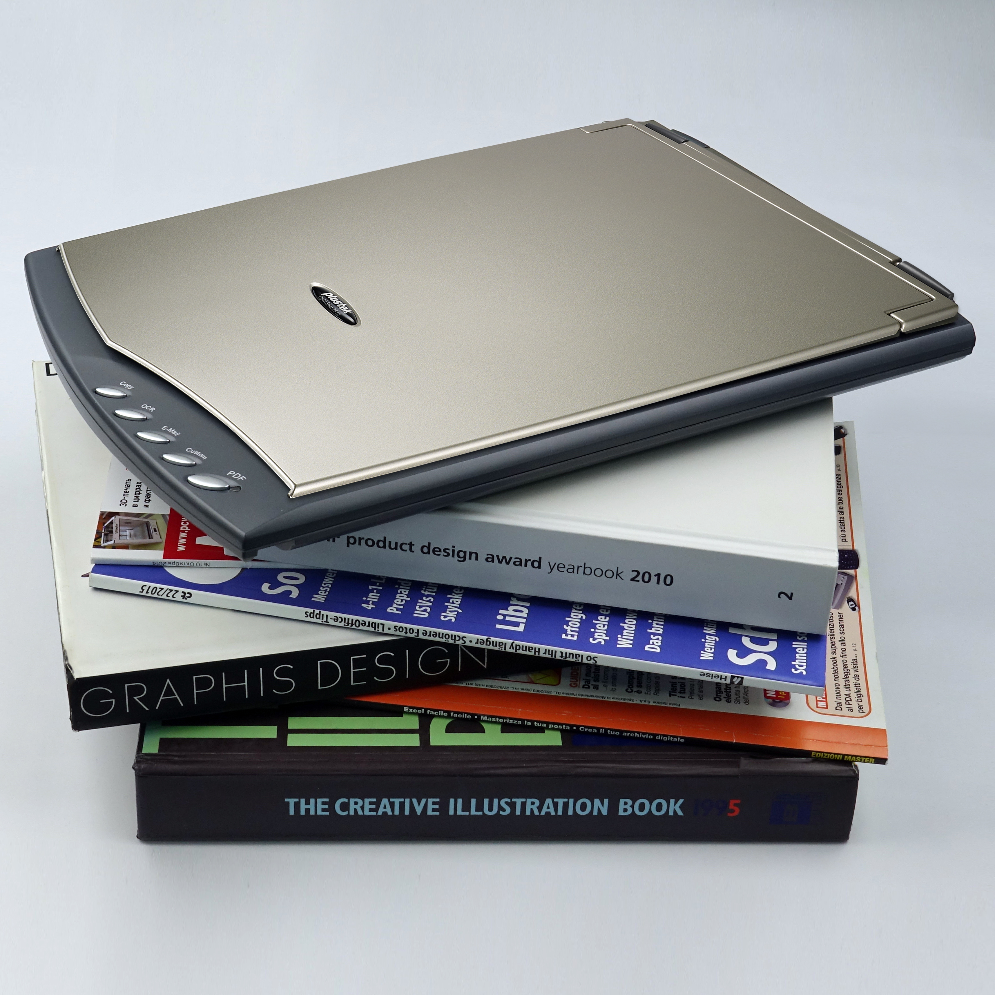 Uno scanner sopra una pila di libri e riviste.