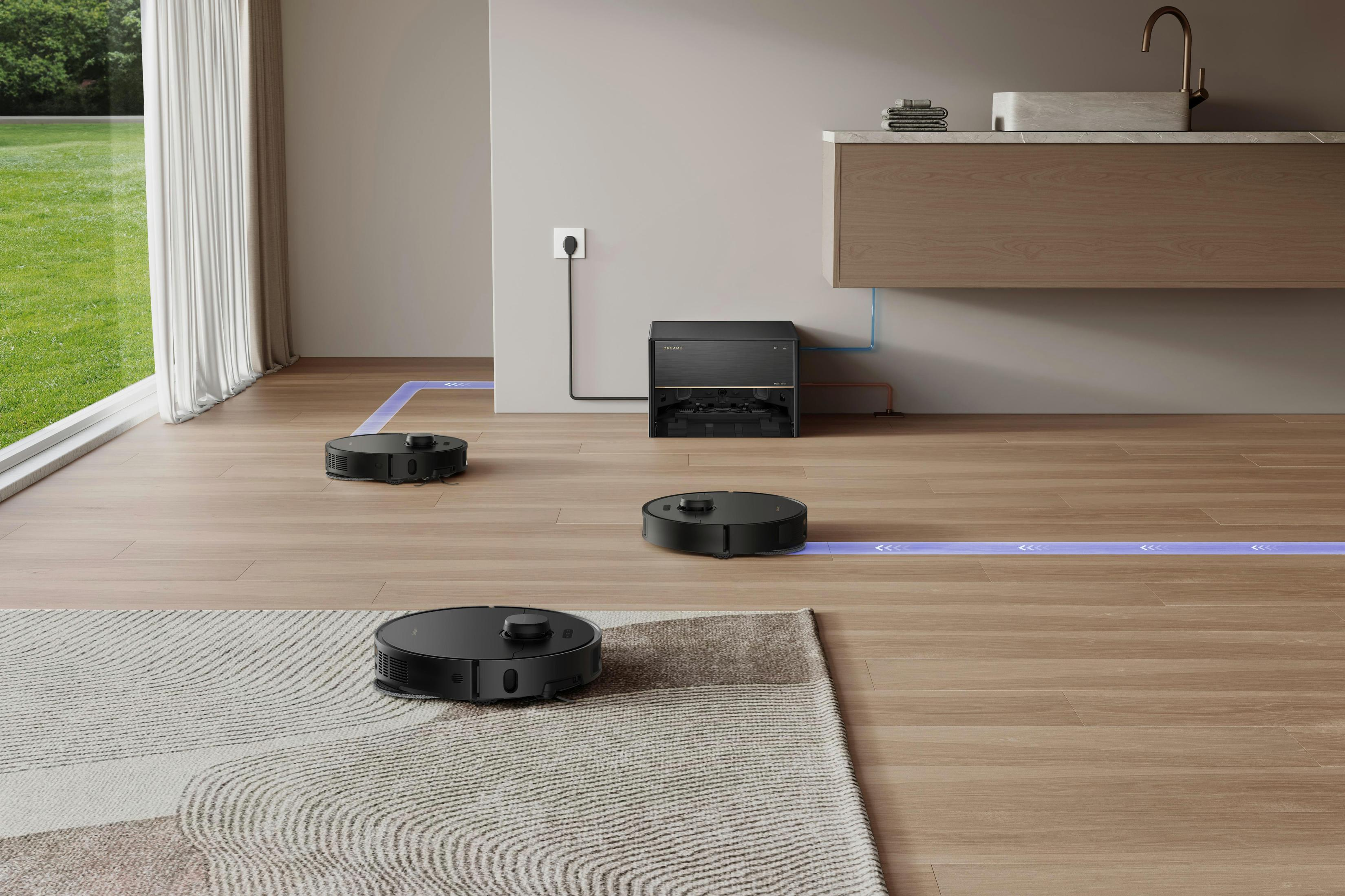 Trzy czarne roboty sprzątające na jasnej drewnianej podłodze. Sprzątają pokój z dywanem.