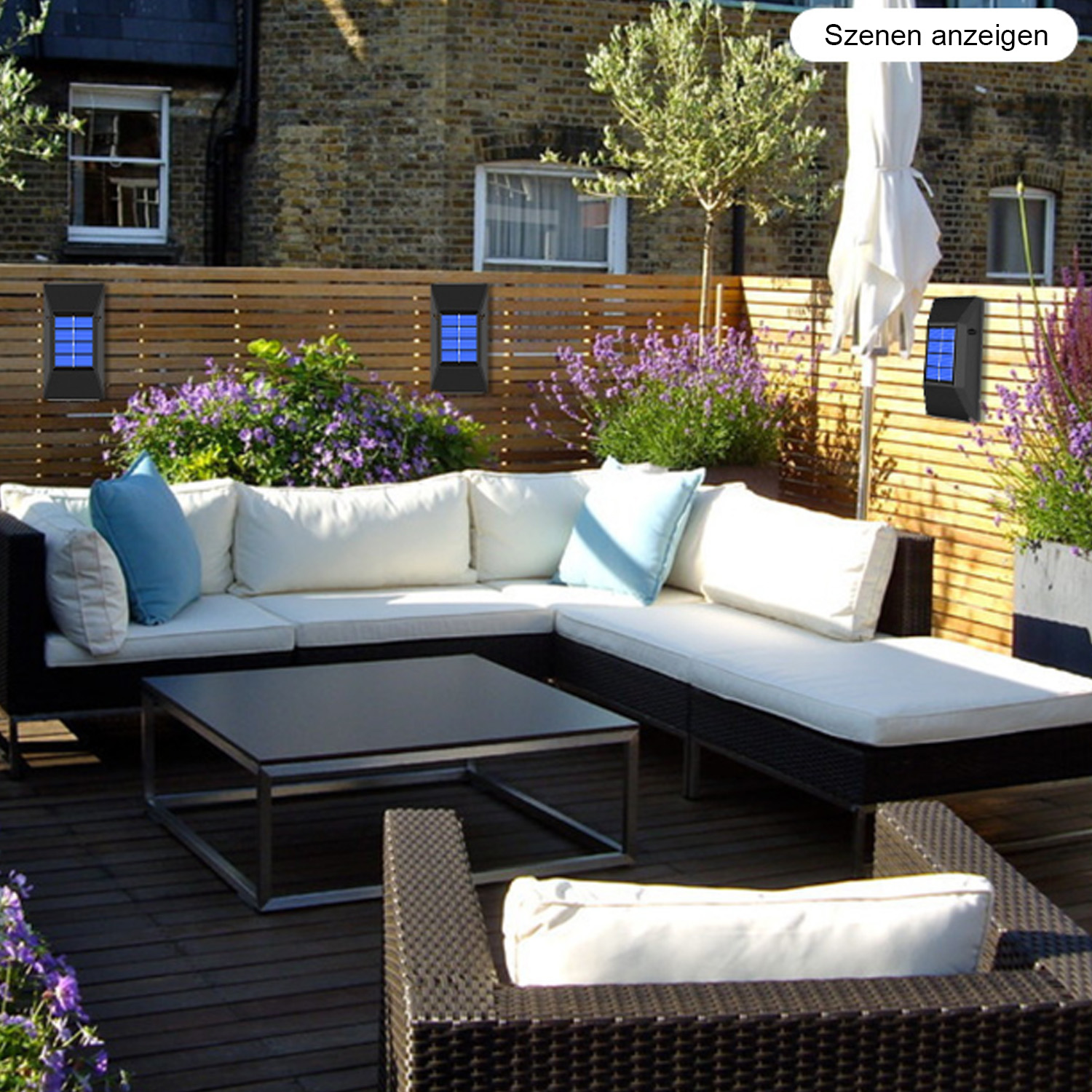 Terrasse mit weißem Sofa, schwarzem Tisch, lila Blumen, Holzzaun und schwarzen Solarleuchten.