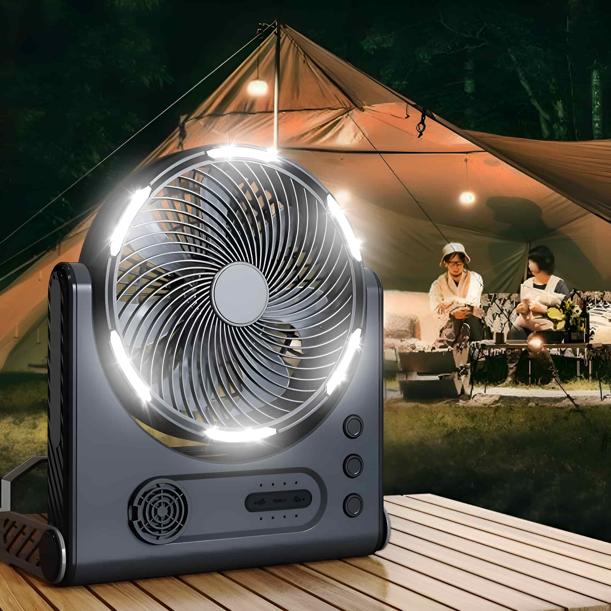 Ein grauer Ventilator mit einem Lichtring oben. Im Hintergrund sitzen zwei Personen in der Nähe eines Zeltes.
