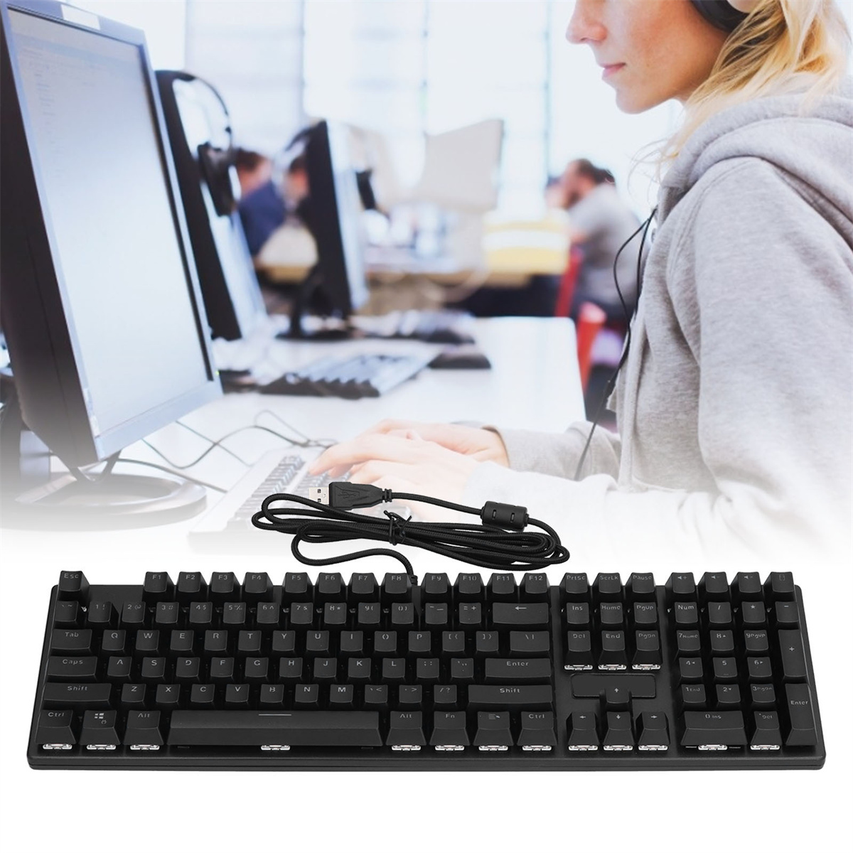 Schwarze Tastatur mit weißen Buchstaben. Person benutzt Computer im unscharfen Hintergrund.