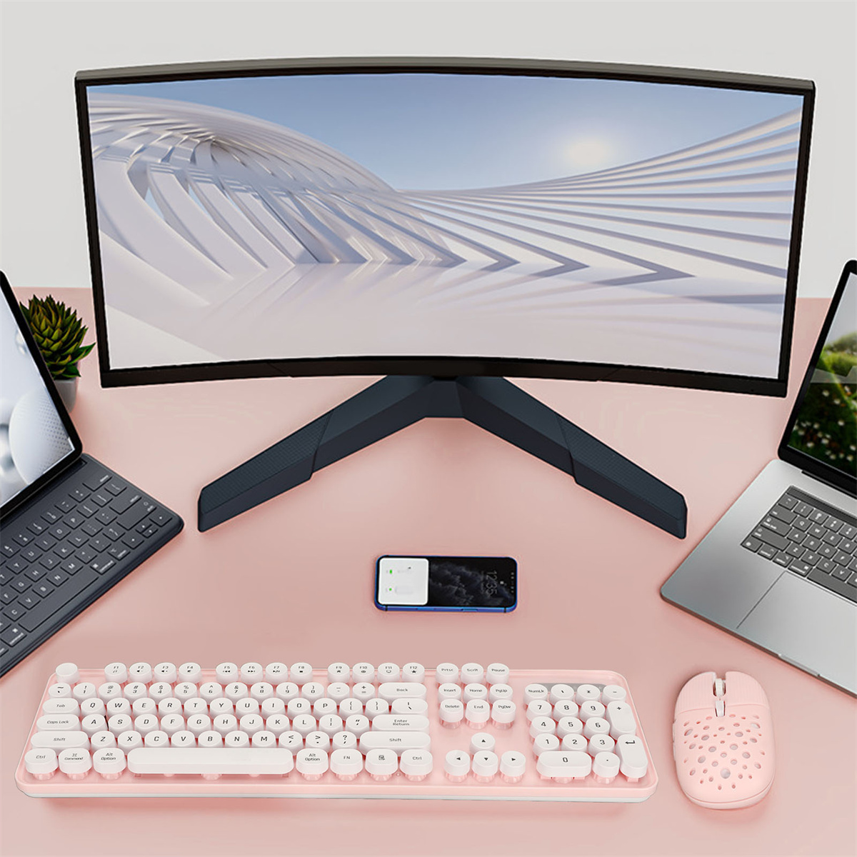 Rosa Schreibtisch-Setup: gebogener Monitor, zwei Laptops, Telefon, pinke Tastatur und Maus.