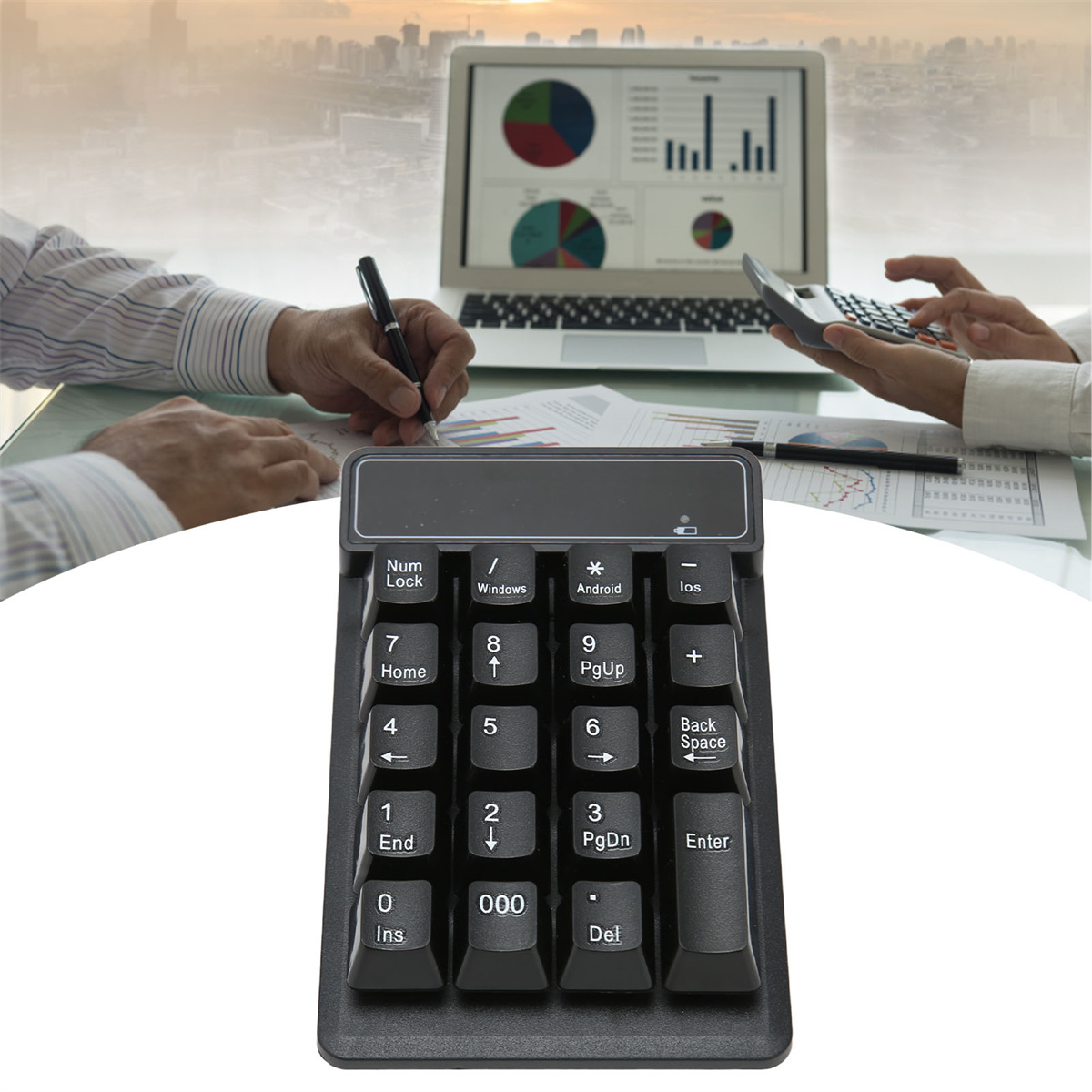 Ein schwarzer numerischer Tastenblock mit Laptop und Diagrammen im Hintergrund, zwei Personen arbeiten.