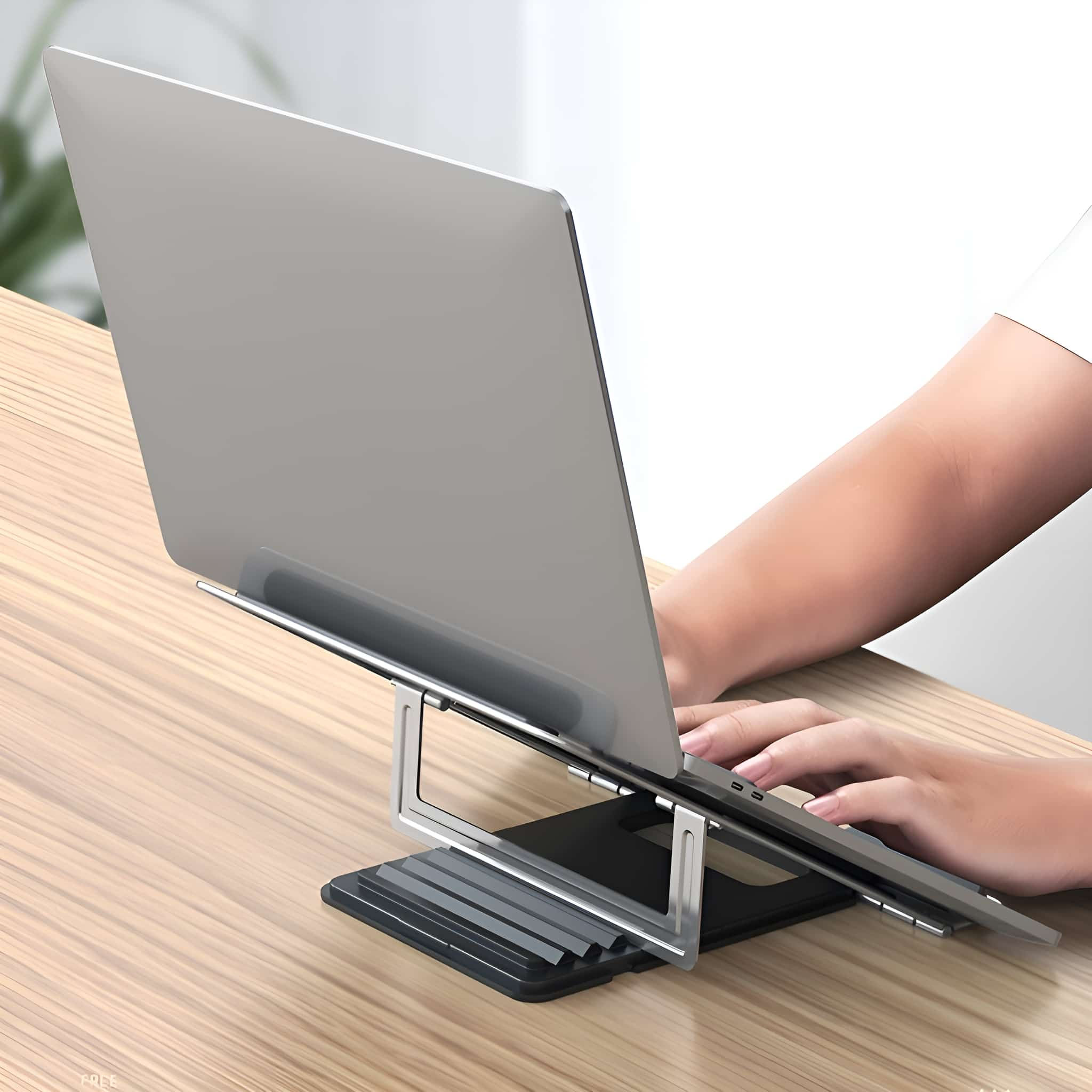 Ein Laptop auf einem silbernen Ständer, nach oben geneigt, auf einem Holzschreibtisch platziert.