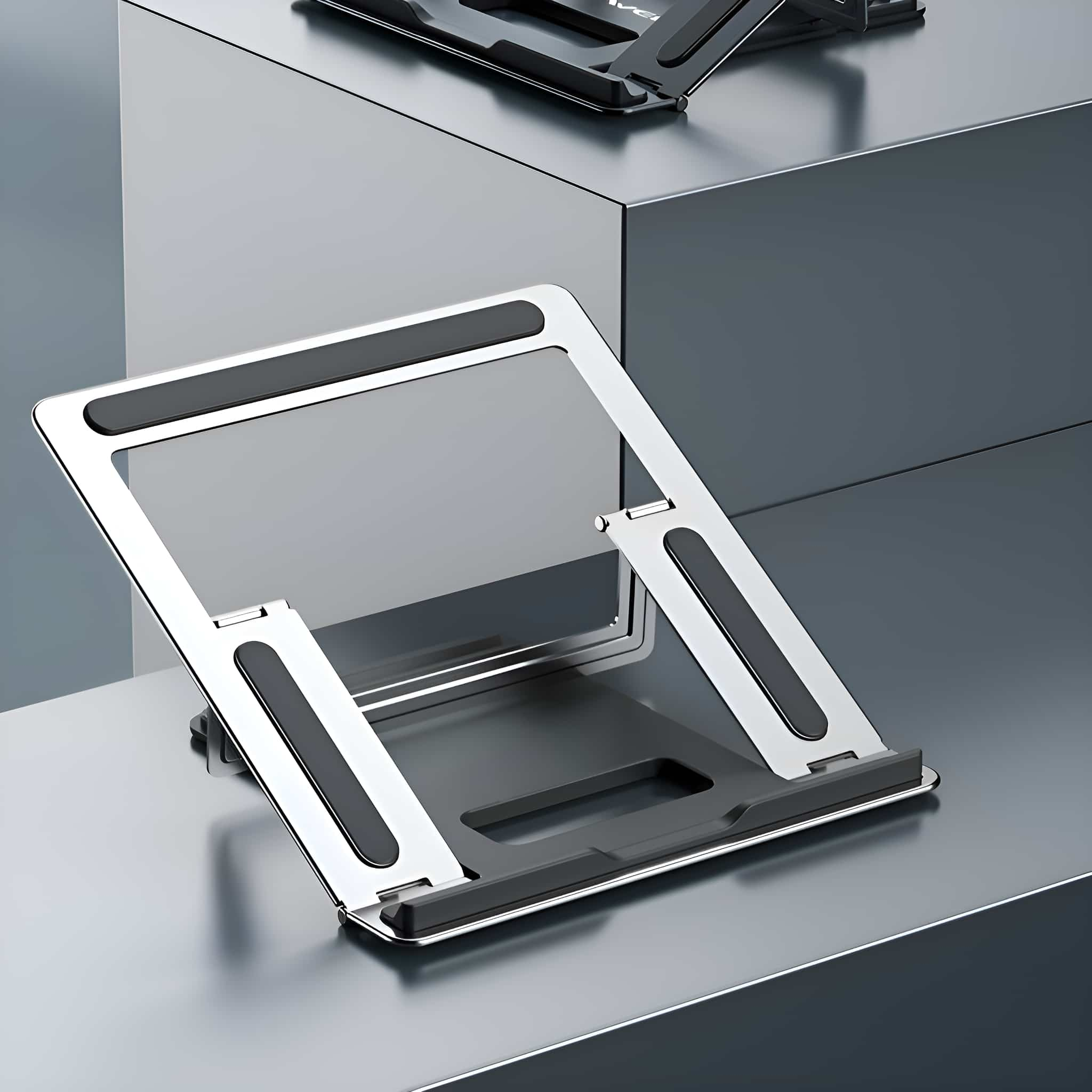 Ein silberner Laptop-Ständer mit schwarzen Pads auf einer Metalloberfläche.