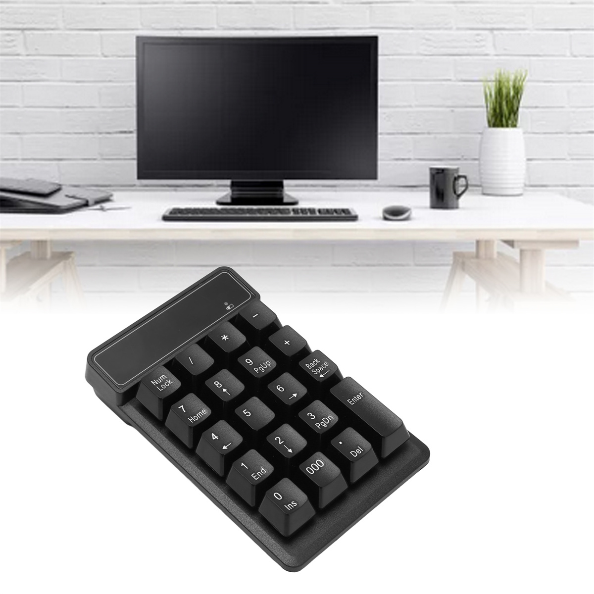Ein schwarzer Ziffernblock auf einem Schreibtisch mit einem Computer. Das Tastenfeld hat viele Tasten. Eine Pflanze und eine Tasse sind ebenfalls auf dem Schreibtisch.