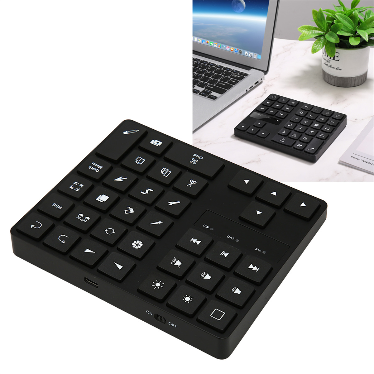 Schwarze Tastatur mit vielen Tasten, darunter Pfeile und Zahlen. Ein Laptop und eine weitere Tastatur liegen auf dem Tisch.