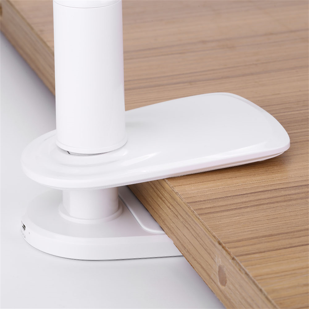 Weißer Schreibtischlampenfuß an Holzoberfläche befestigt. Modernes, minimalistisches Design.