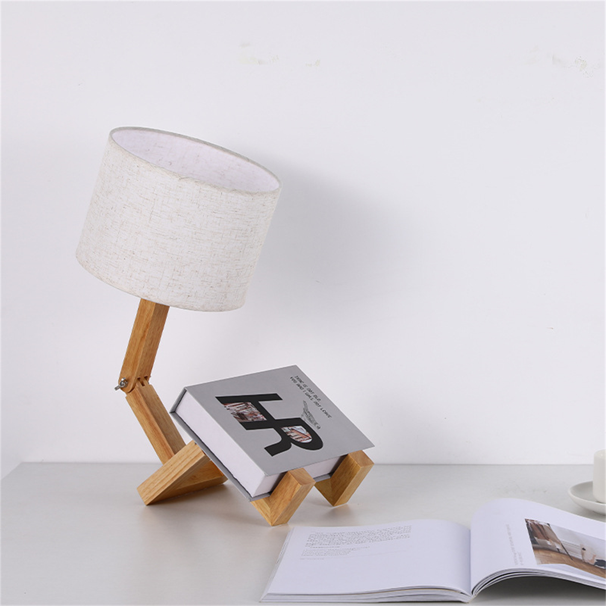 Eine Holzlampe steht auf einem Buch. Ein Buch und eine weitere Lampe befinden sich im Hintergrund.