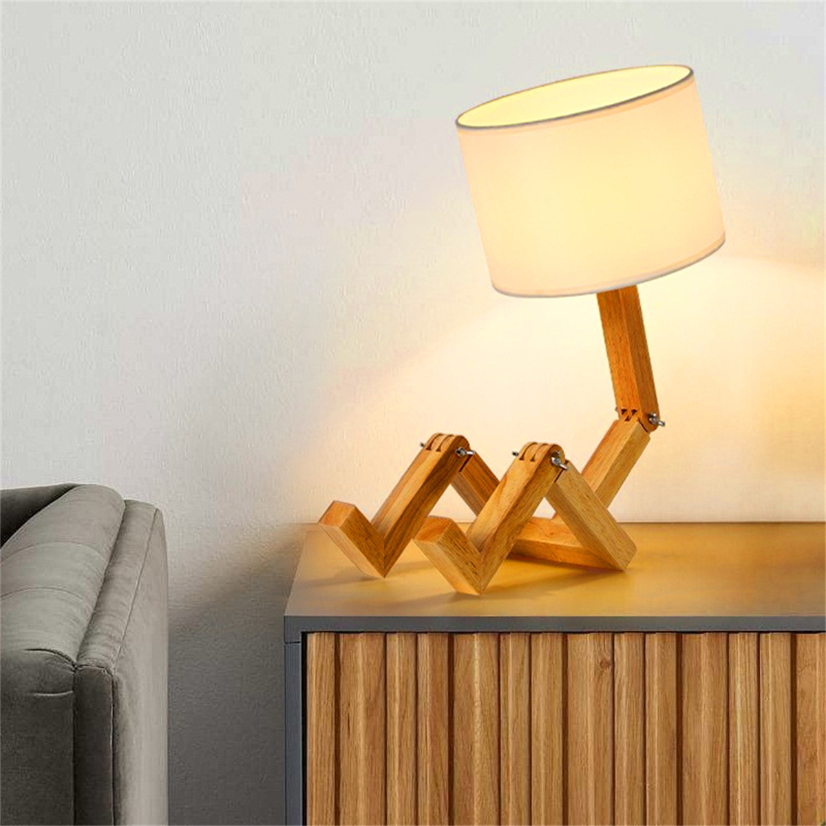 Eine hölzerne Lampe in Form einer sitzenden Person. Die Lampe hat einen weißen Lampenschirm.