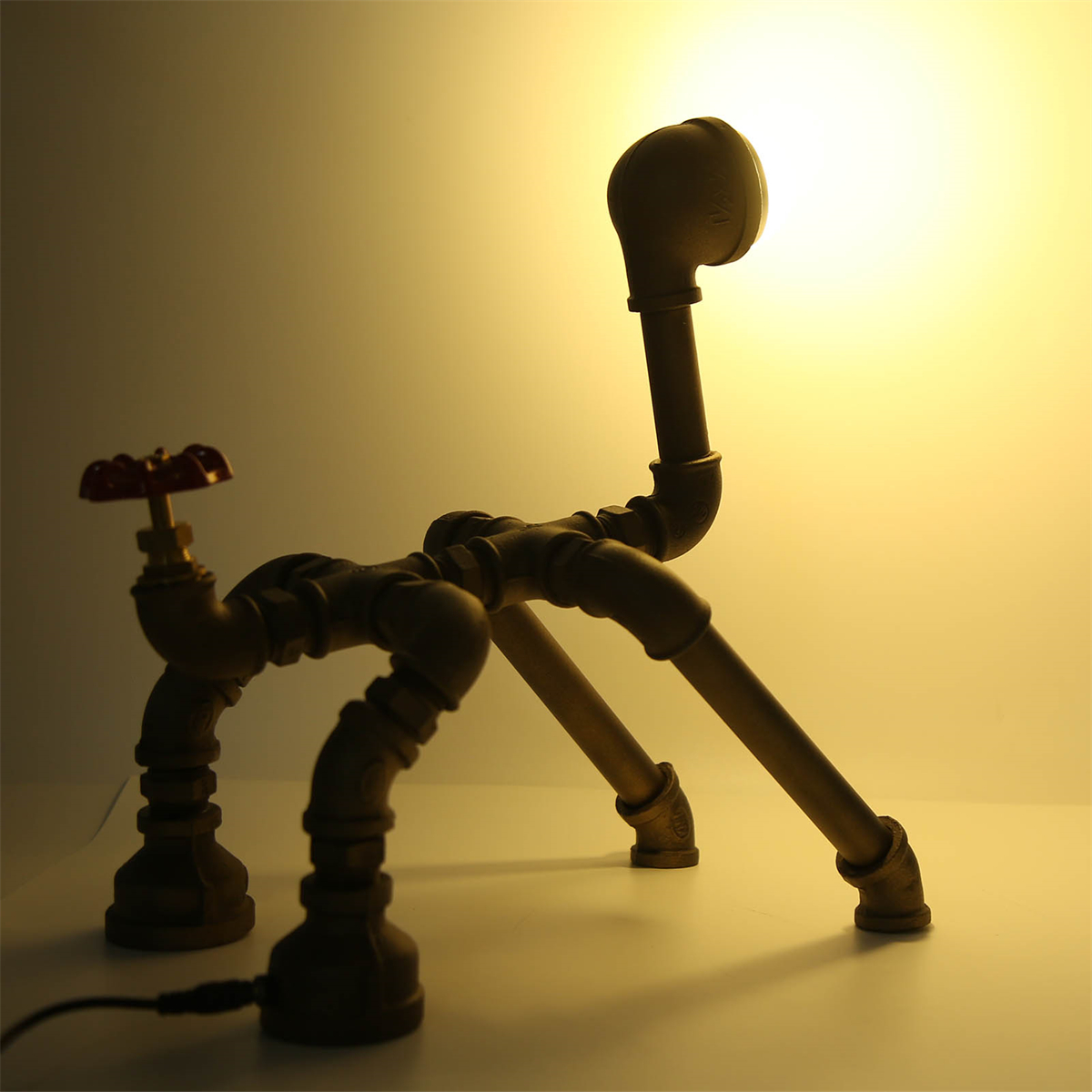 Eine einzigartige Lampe aus Rohren. Ein rotes Ventil links, Licht scheint von oben.