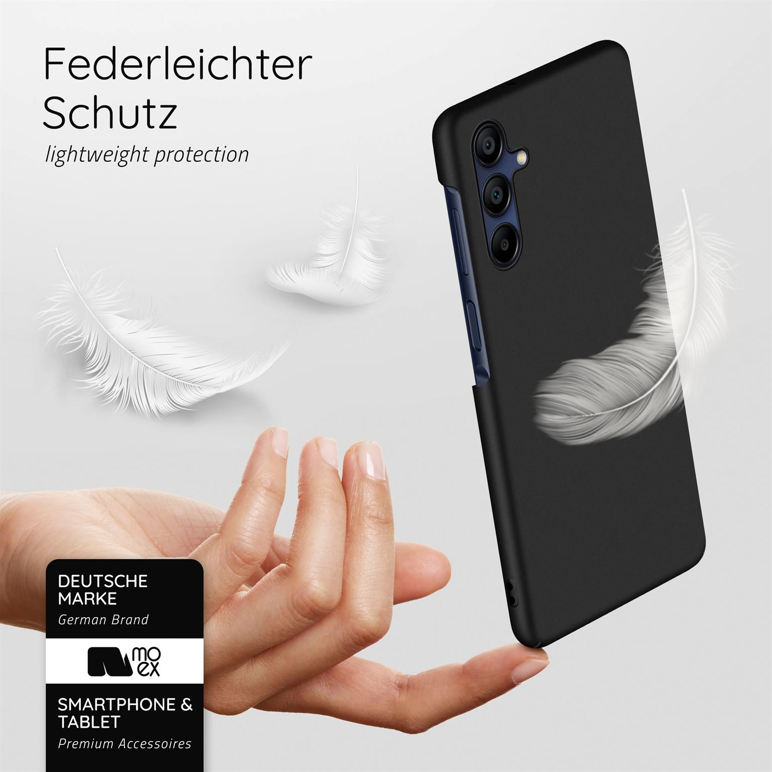 Eine Hand hält eine schwarze Handyhülle mit Federn, die darum schweben. Die Handyhülle ist auf einem schwarzen Telefon.