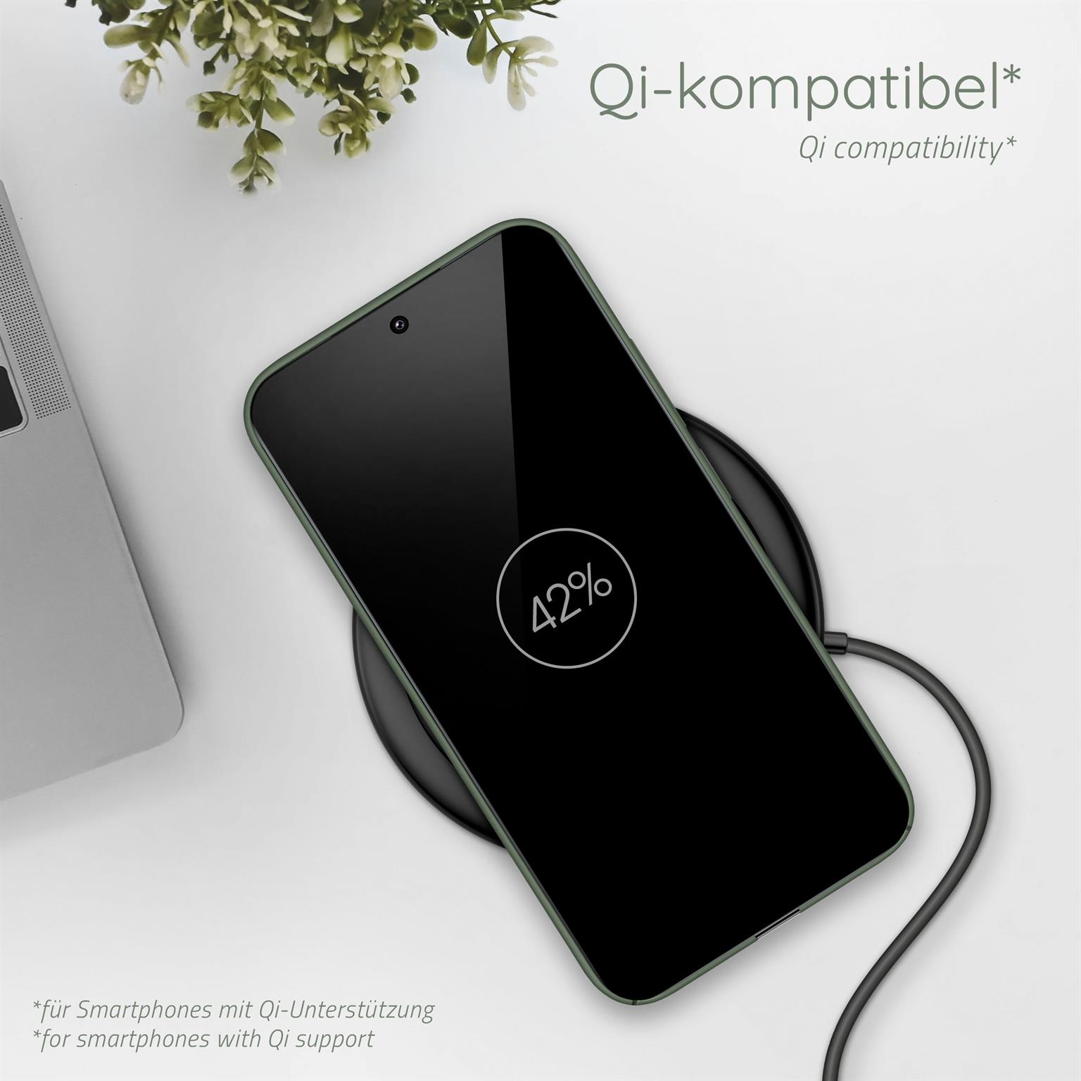 Ein Telefon auf einem kabellosen Ladegerät. Das Telefon hat eine grüne Hülle. Grünzeug im Hintergrund.