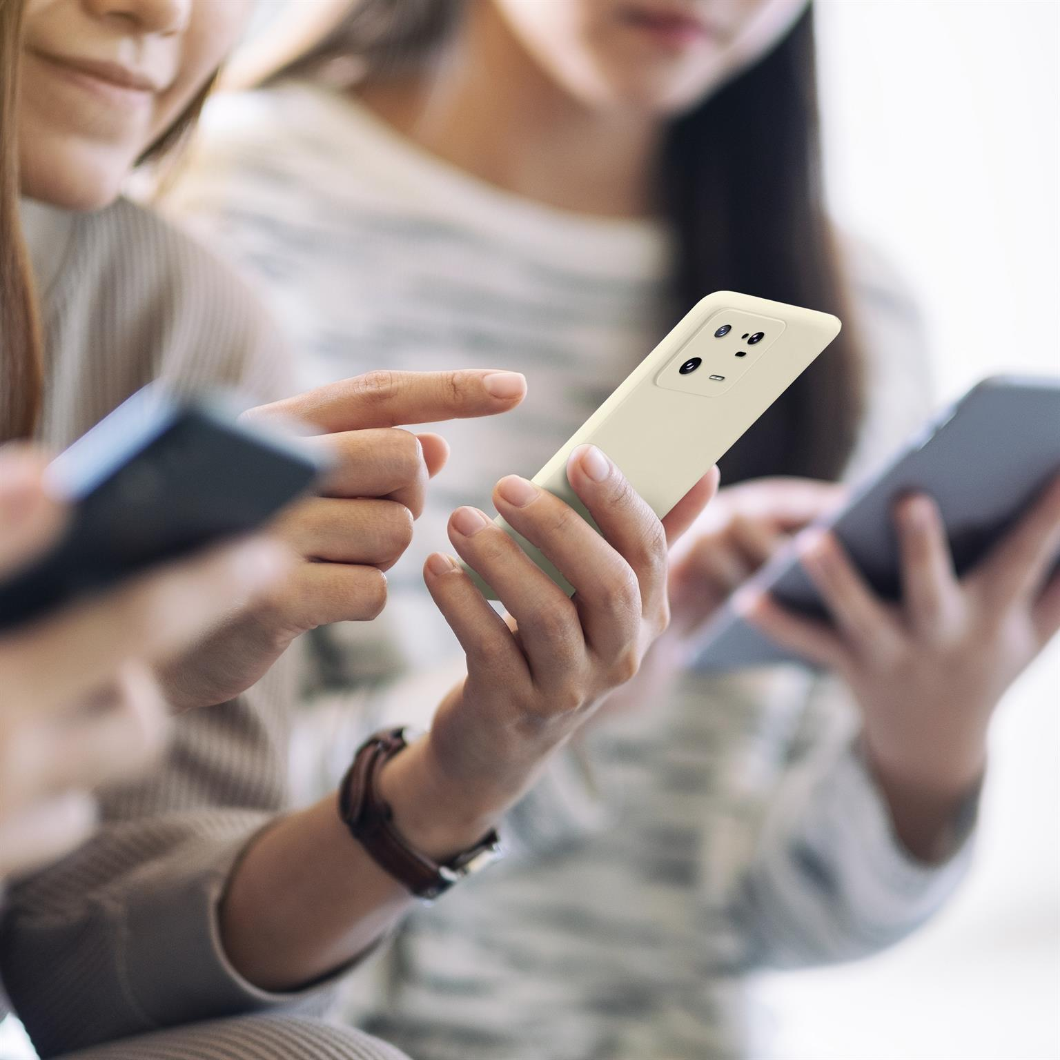 Drei Personen halten Telefone, eine Person hält eine cremefarbene Handyhülle.