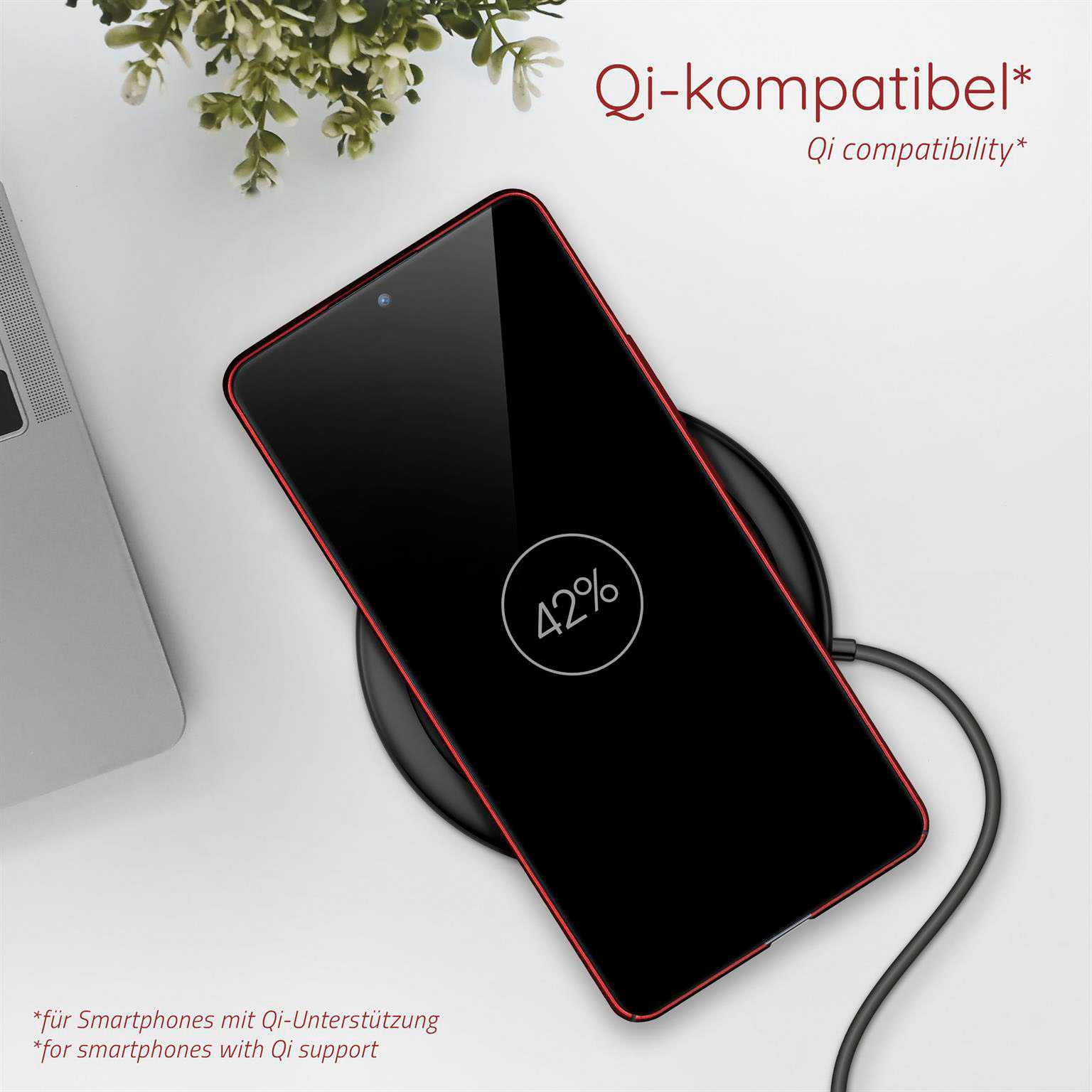 Ein schwarzes Smartphone mit rotem Rand wird auf einem schwarzen kabellosen Ladegerät geladen. 42 % werden angezeigt.