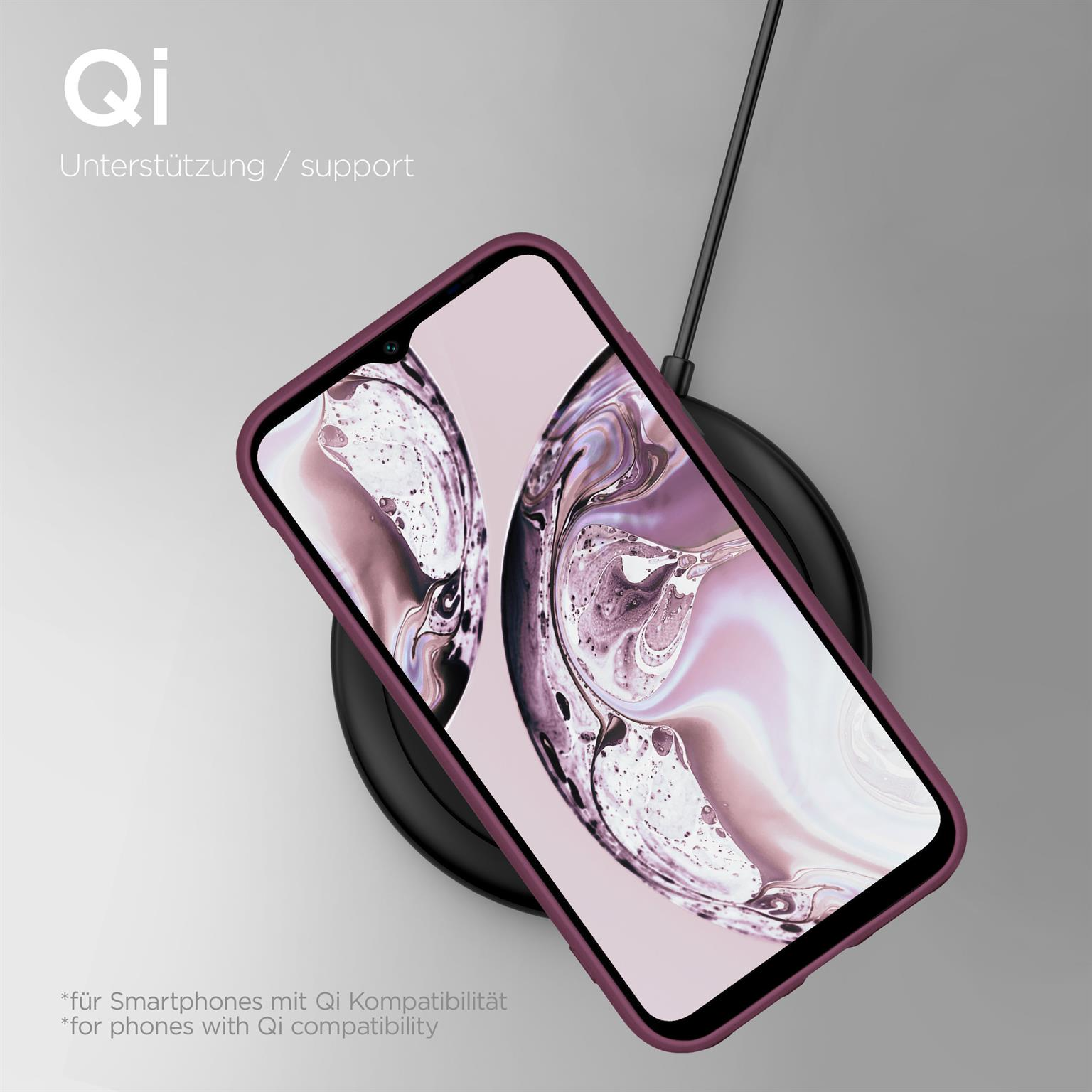 Telefon in rosa Hülle, kabellos auf schwarzem Ladepad geladen, heller Hintergrund.