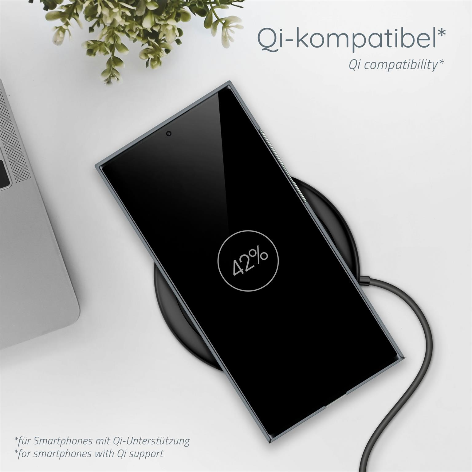 Ein schwarzes Telefon, das auf einem kabellosen Ladegerät geladen wird. Der Telefonbildschirm zeigt 42 % Ladung an. Ein Laptop ist im Hintergrund.
