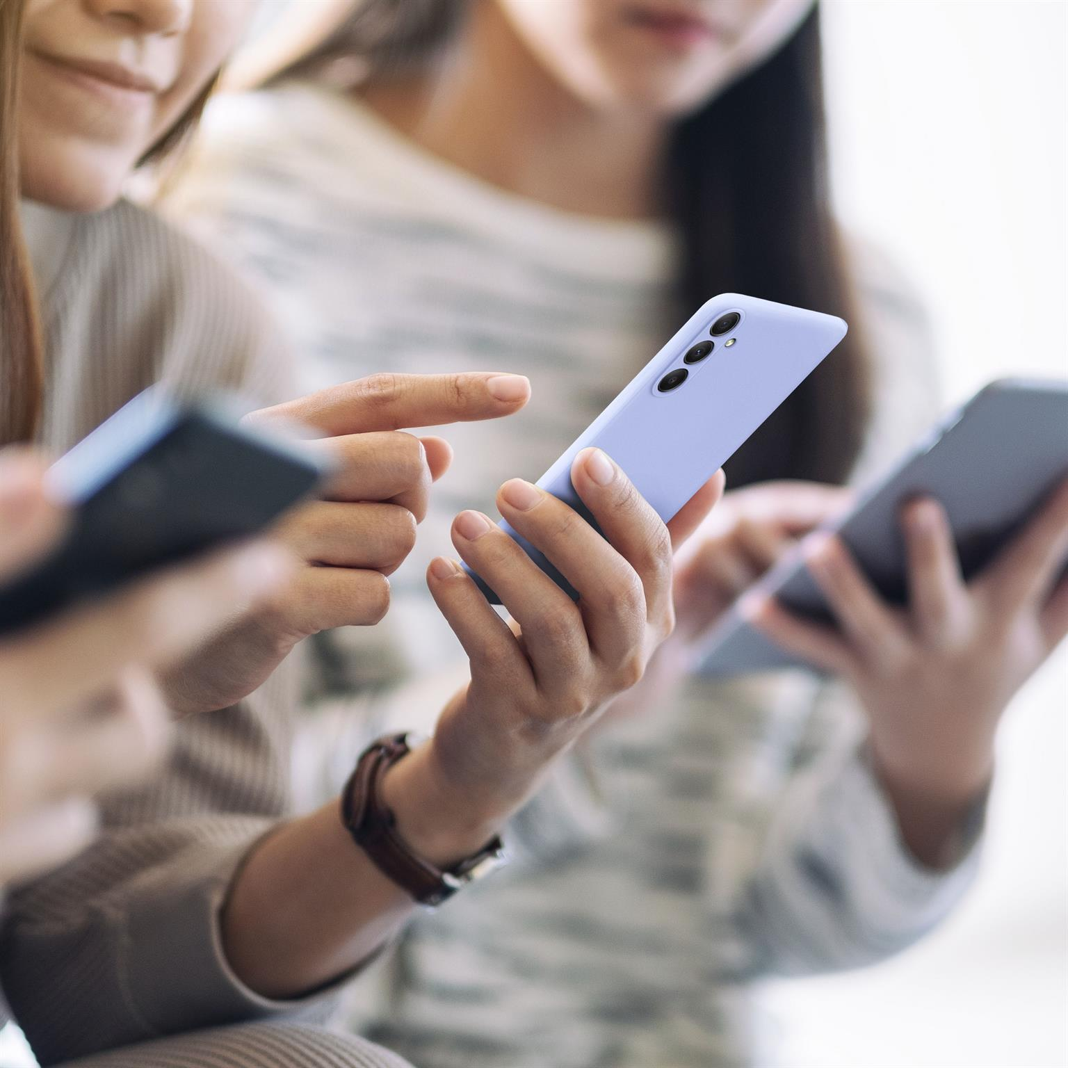 Personengruppe nutzt Telefone. Einer hält ein blaues, andere graue Telefone.