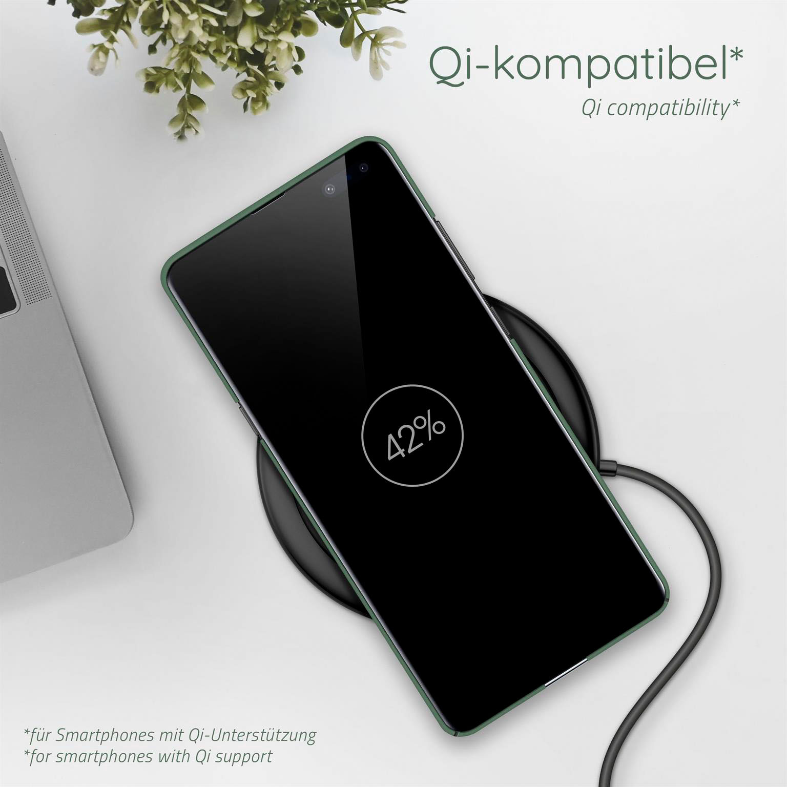 Ein Telefon auf einem kabellosen Ladepad. Auf dem Telefon werden 42% angezeigt. Links ist eine Pflanze. Der Hintergrund ist eine weiße Oberfläche.