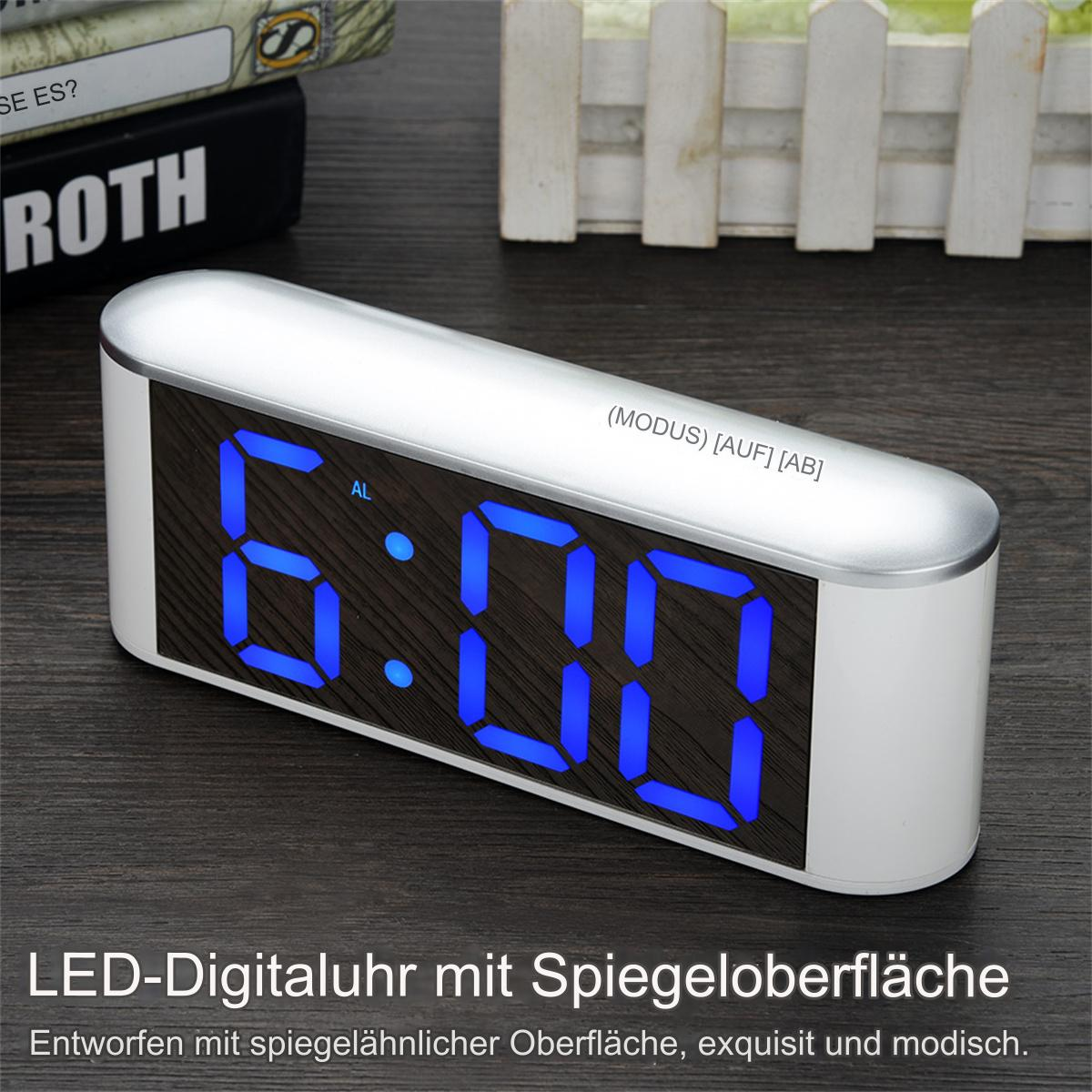 Digitale LED-Uhr mit der Anzeige 6:00, mit blauen Ziffern, auf Holzoberfläche.